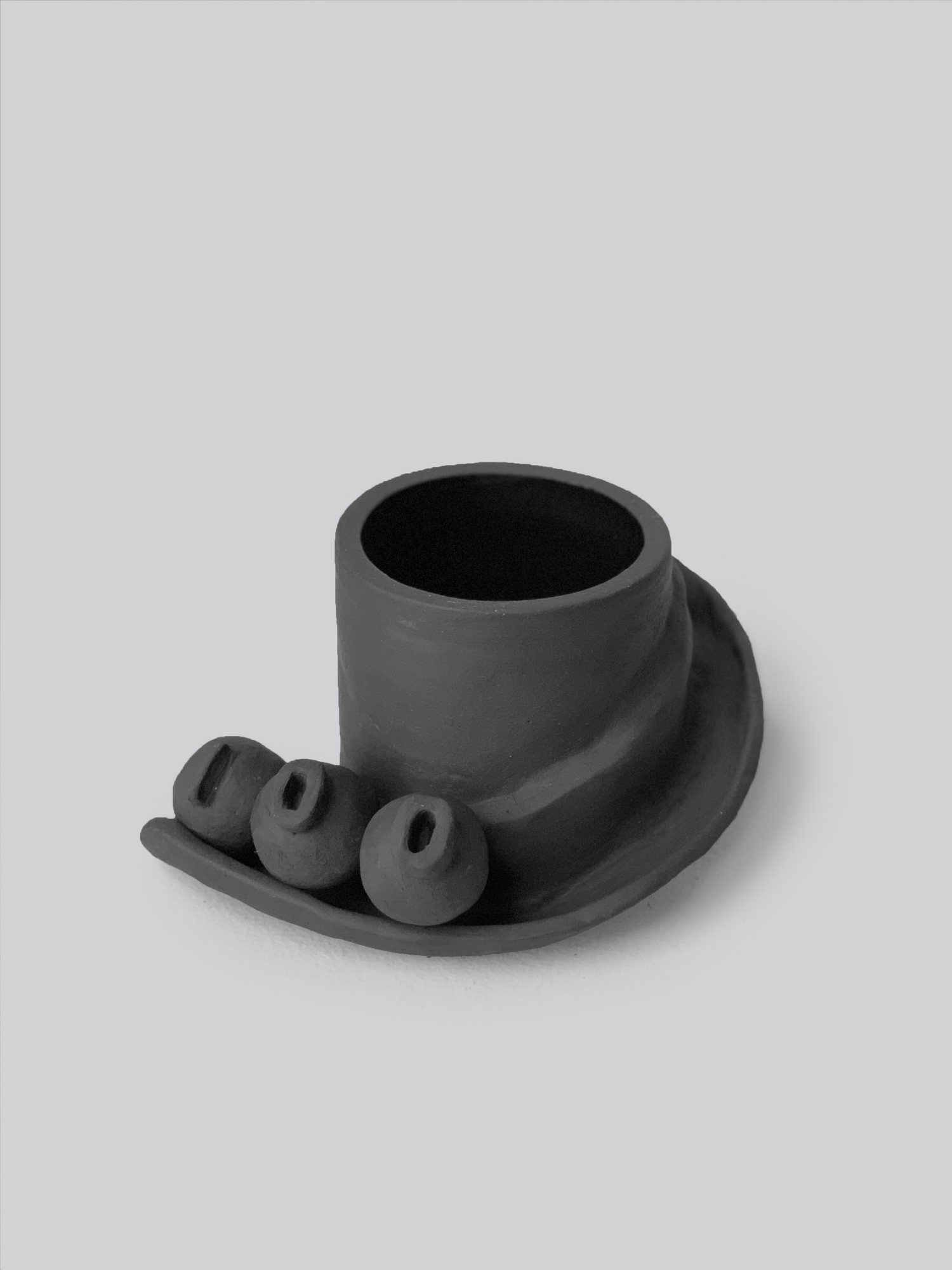 Black matte stoneware ceramic mug with a slide moving down the side of the mug as a handle and three detachable ornamental balls.