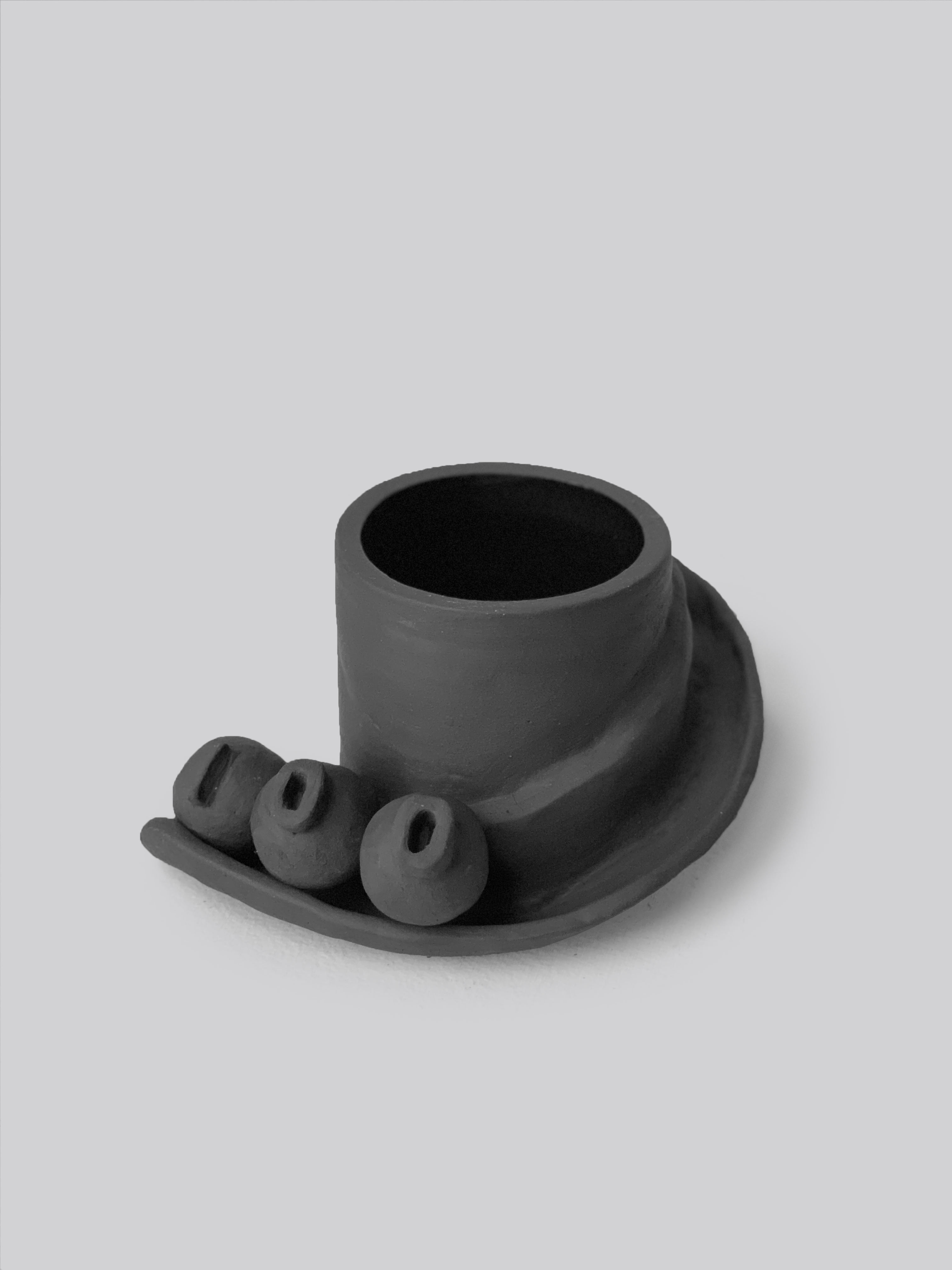 Black matte stoneware ceramic mug with a slide moving down the side of the mug as a handle and three detachable ornamental balls.