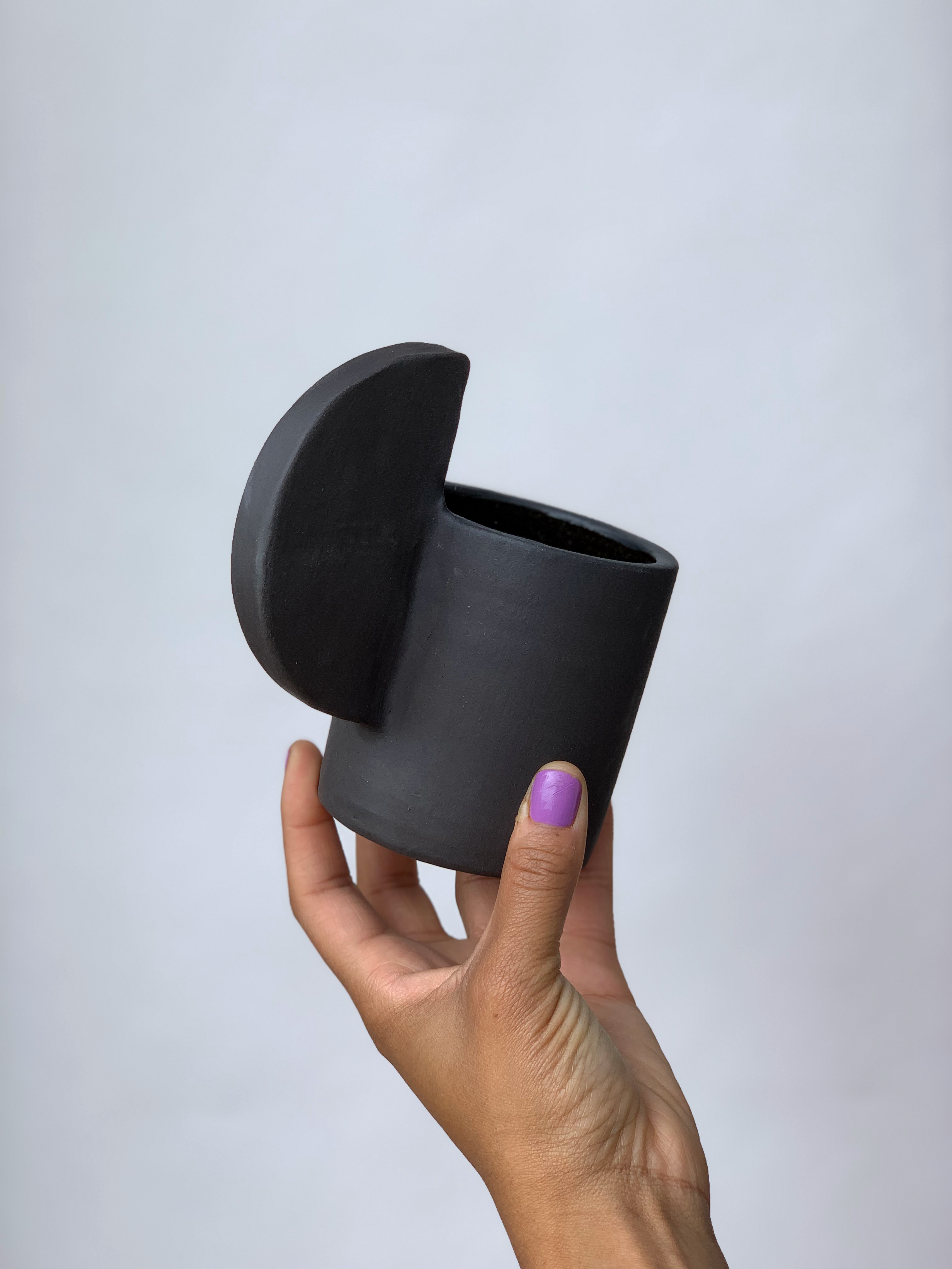 Black matte stoneware ceramic mug with an extended half circle handle.