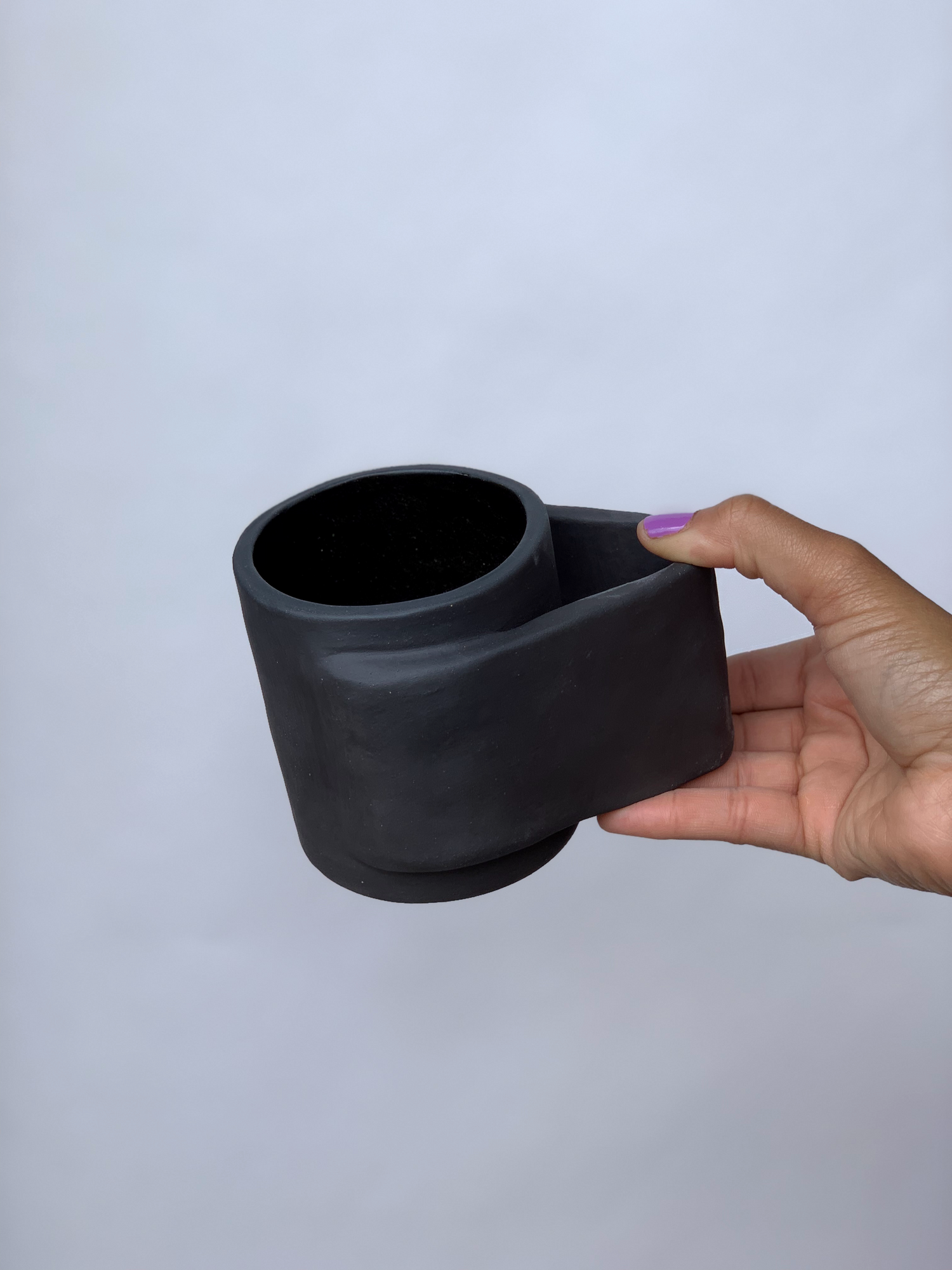 Black matte stoneware ceramic mug with a wide wrap around handle.