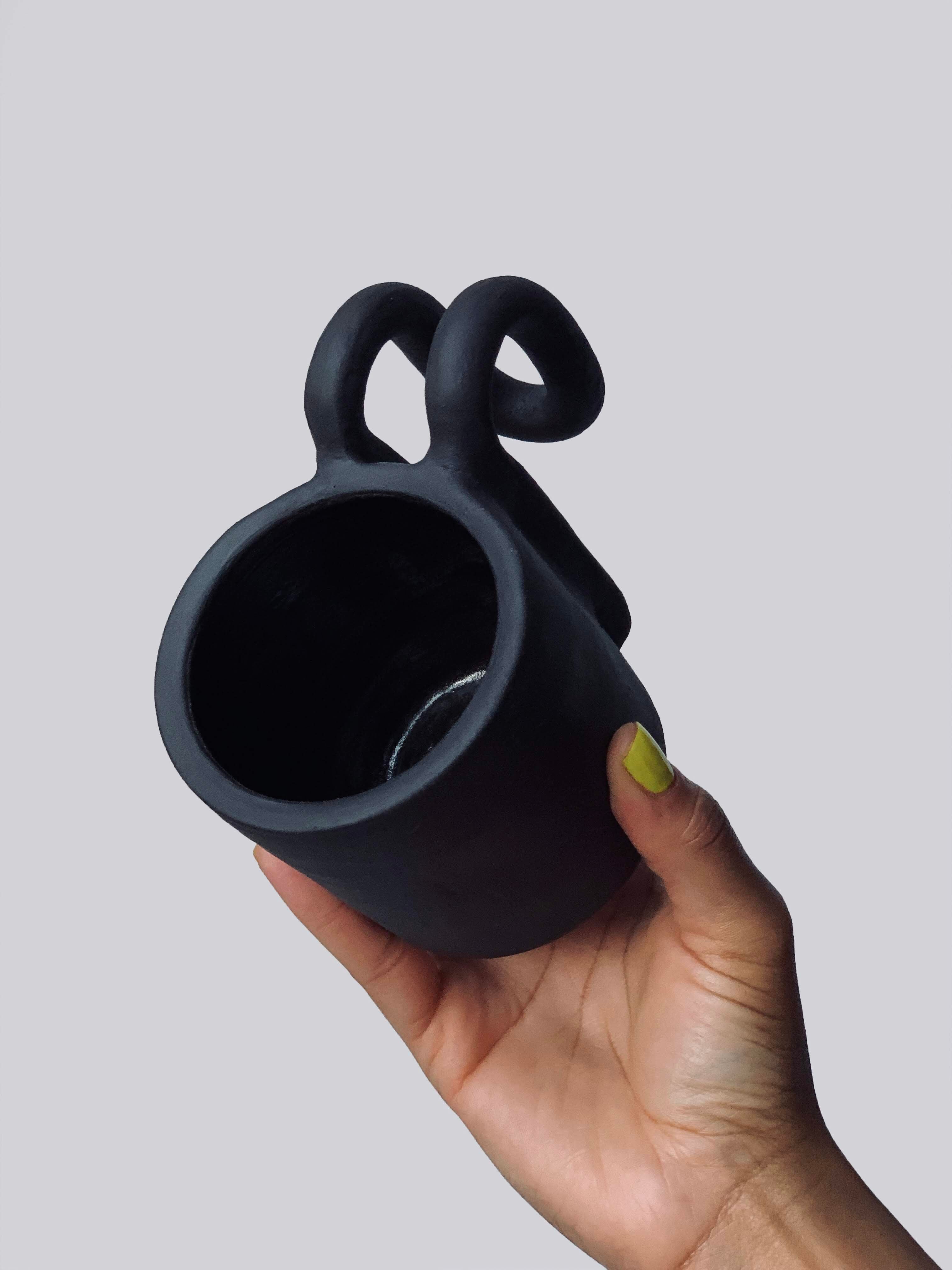 Black matte stoneware ceramic mug with a fold over bar handle.