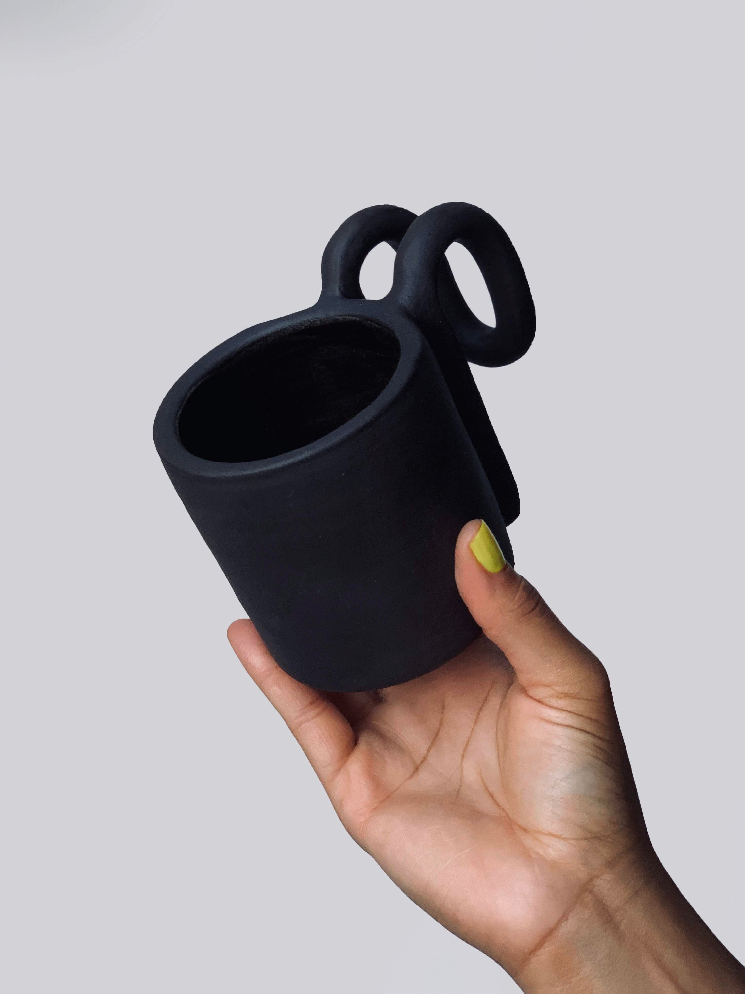 Black matte stoneware ceramic mug with a fold over bar handle.