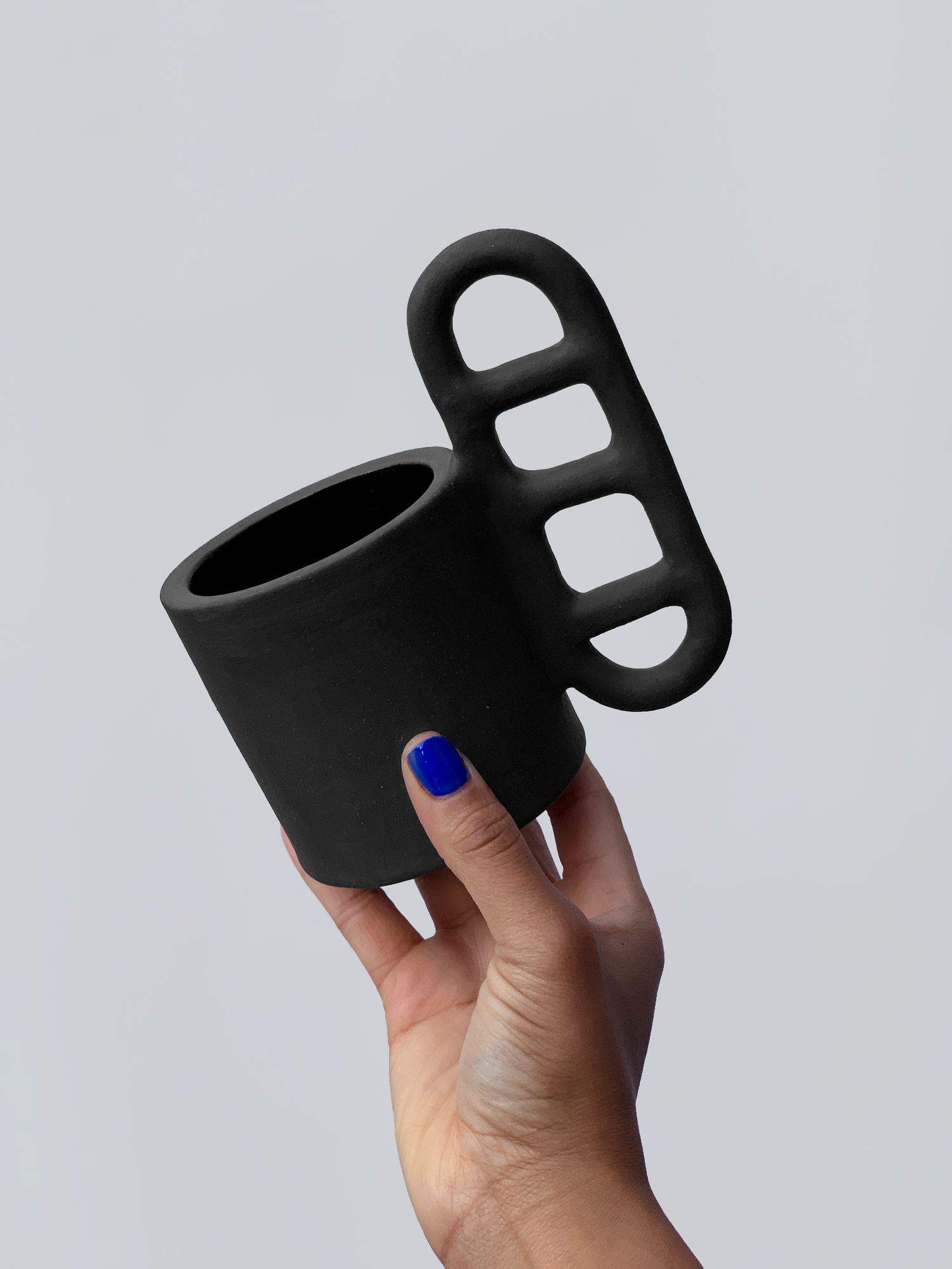 Black matte stoneware ceramic mug with an oval window handle.