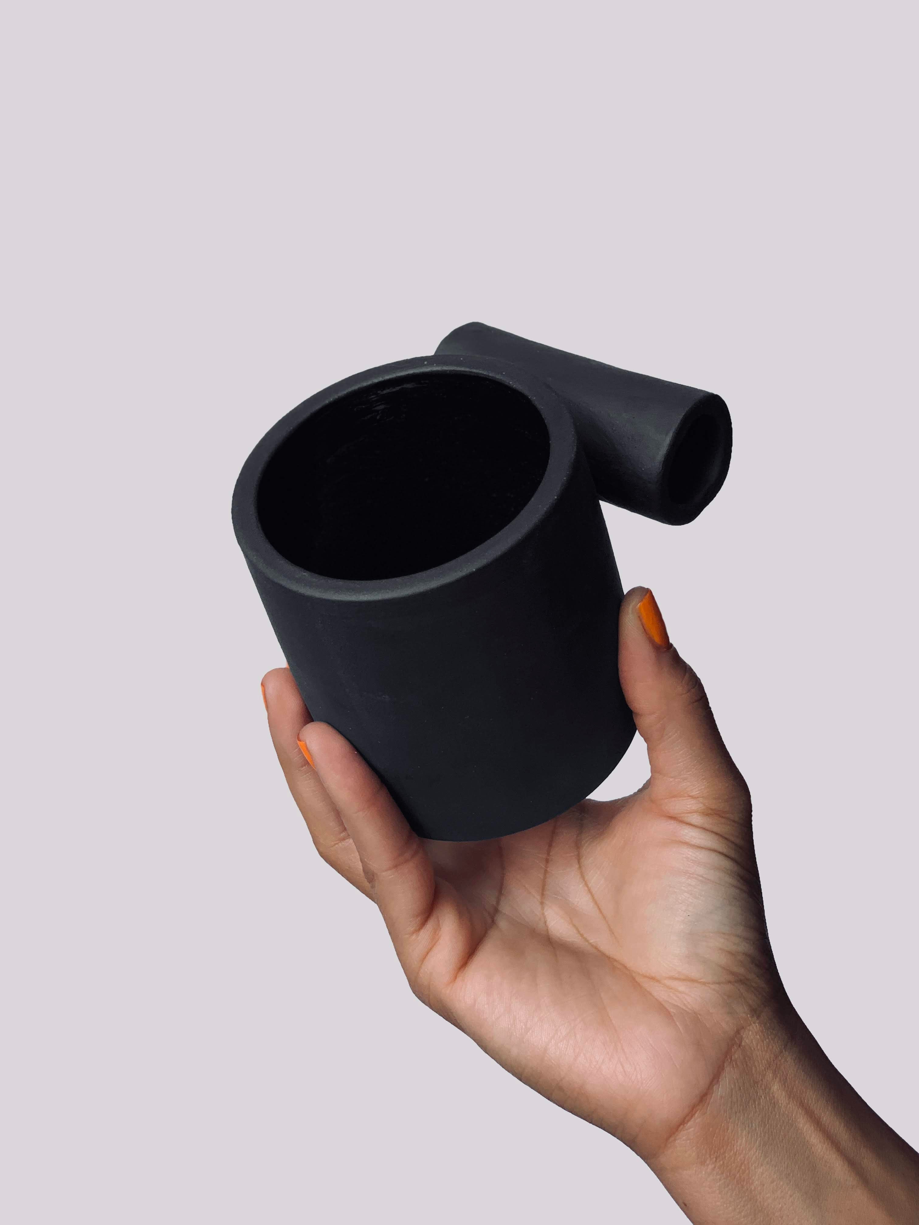 Black matte stoneware ceramic mug with a full side roll as the handle.