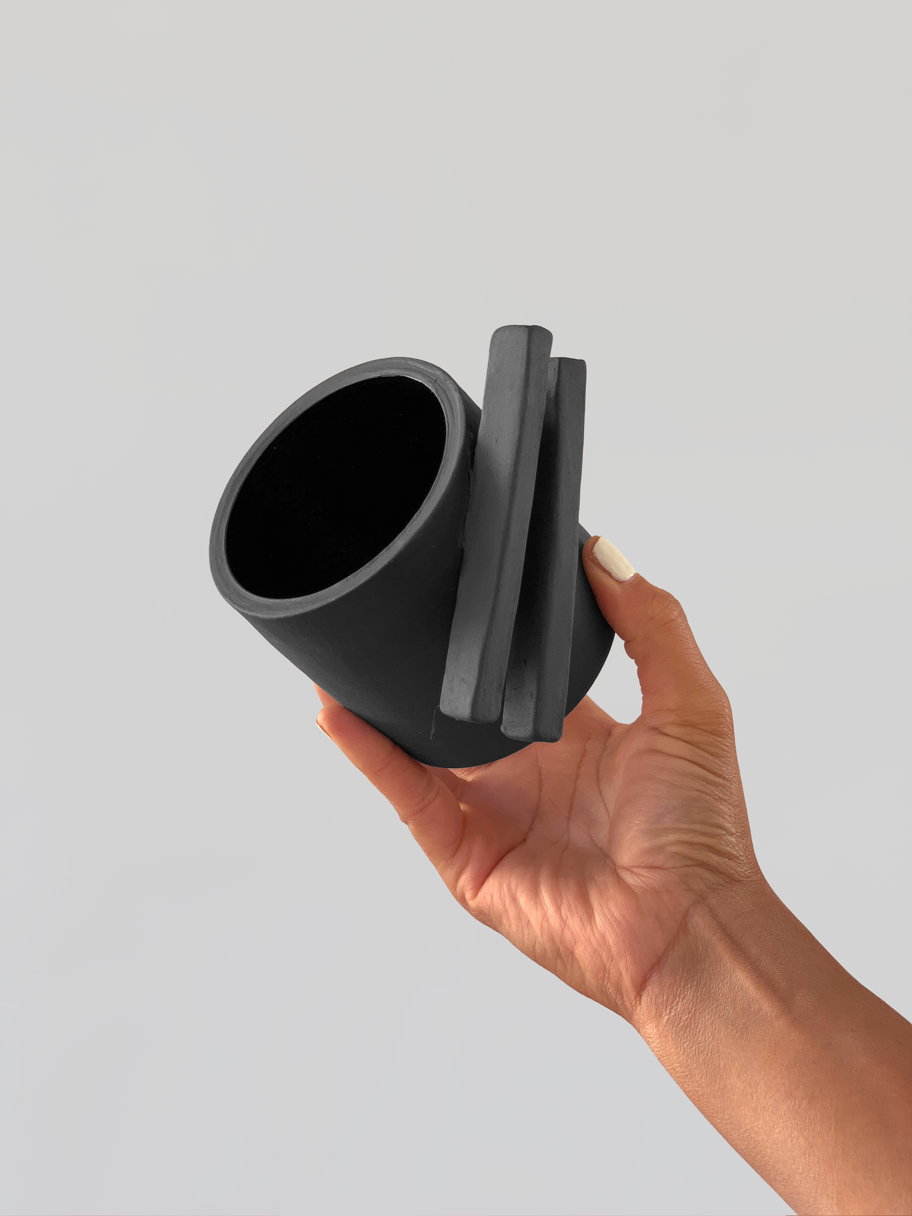 Black matte stoneware ceramic mug with two long rectangle shapes on the side of the mug as the handle.