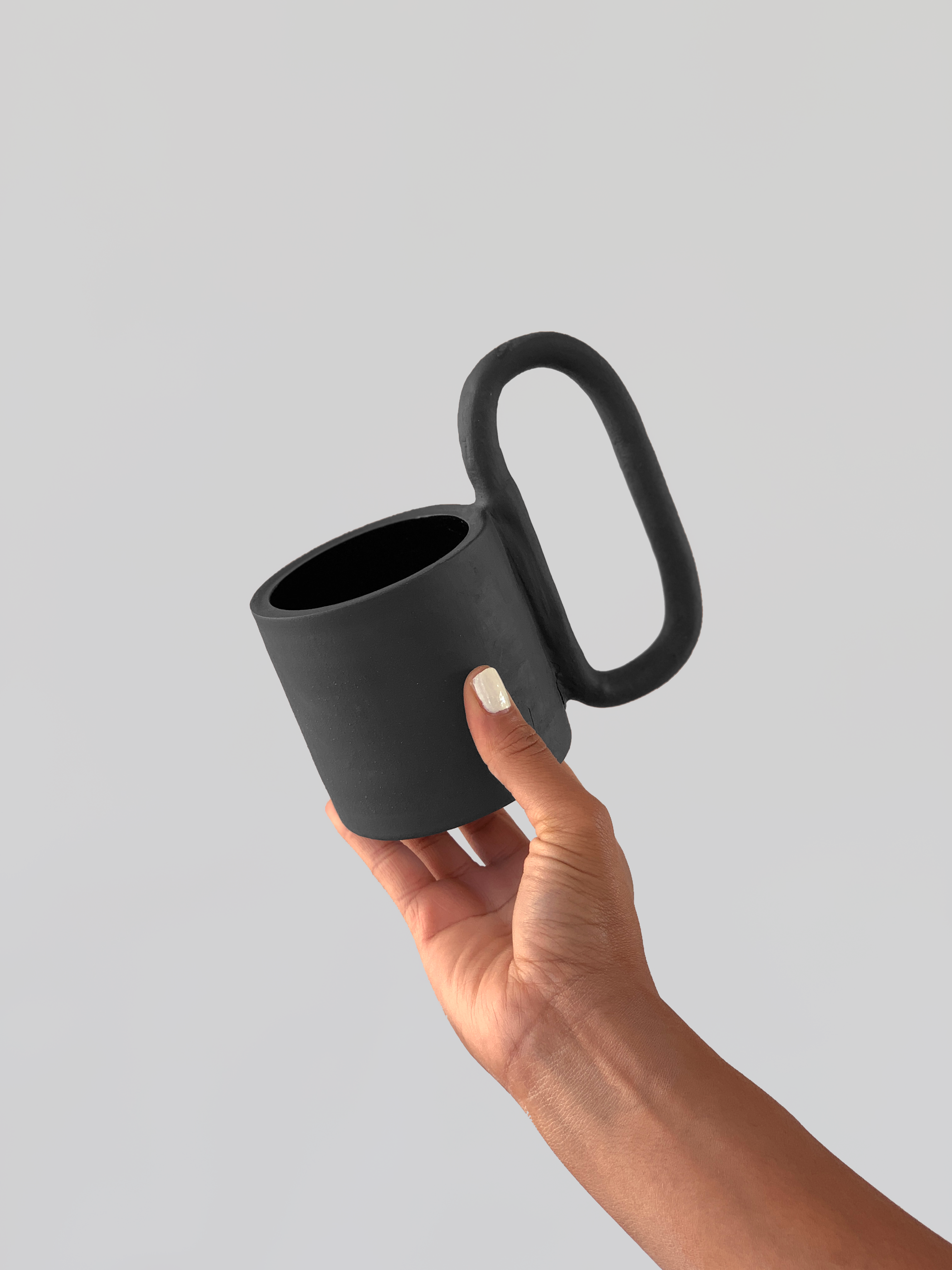 Black matte stoneware ceramic mug with a n extended oval handle.