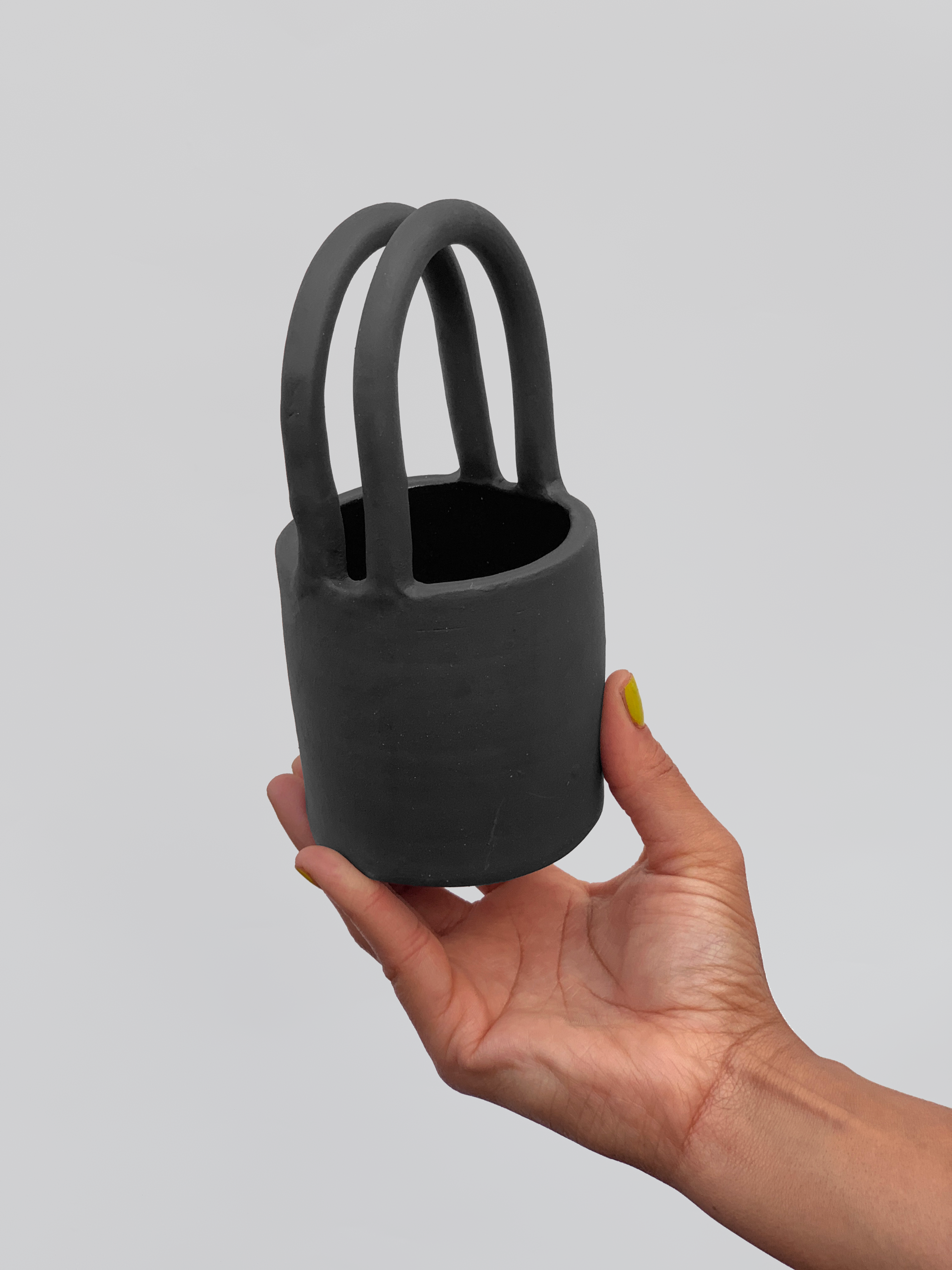 Black matte stoneware ceramic mug with tote bag handles.