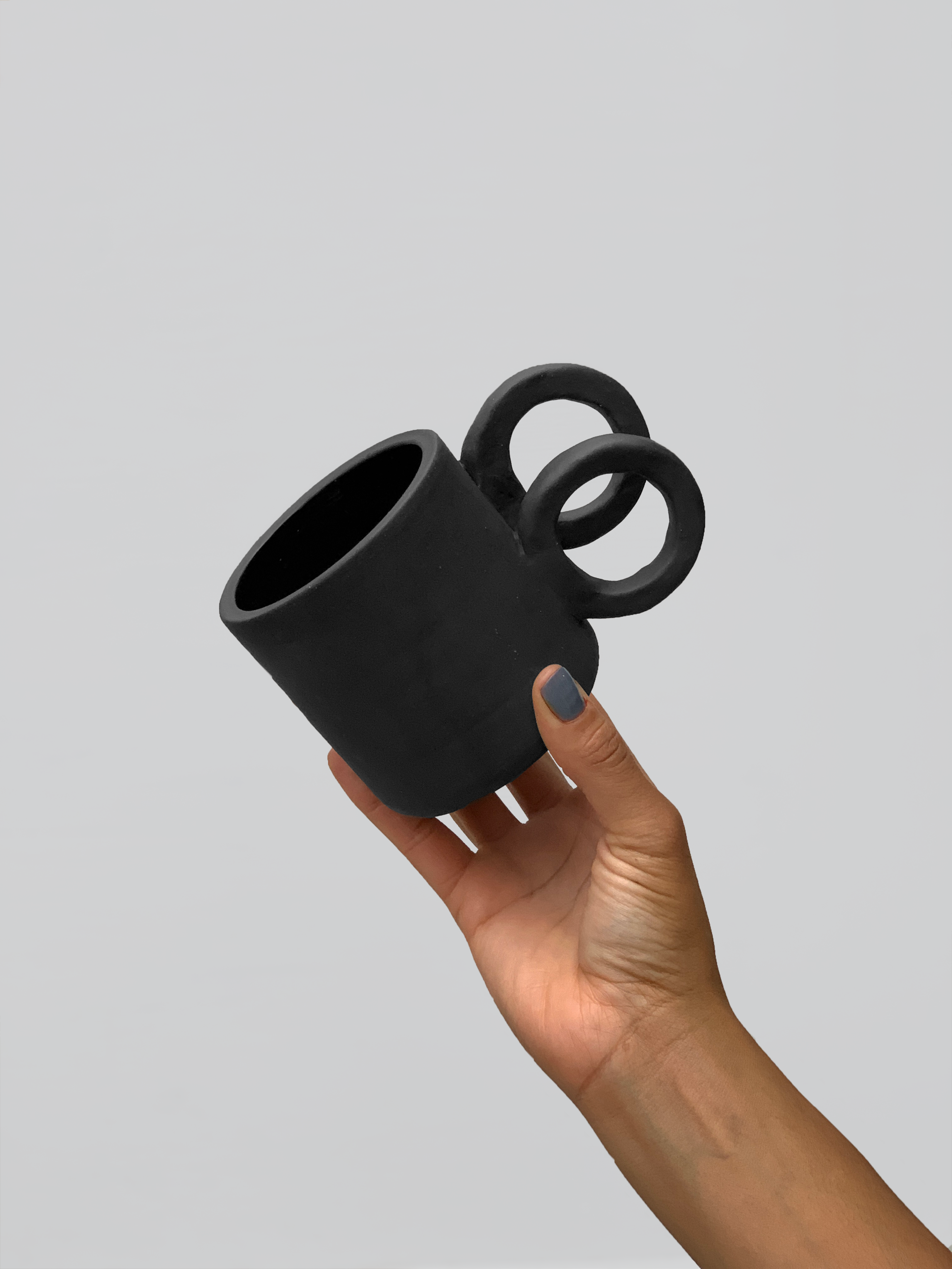 Black matte stoneware ceramic mug with side staggered full circle handles.