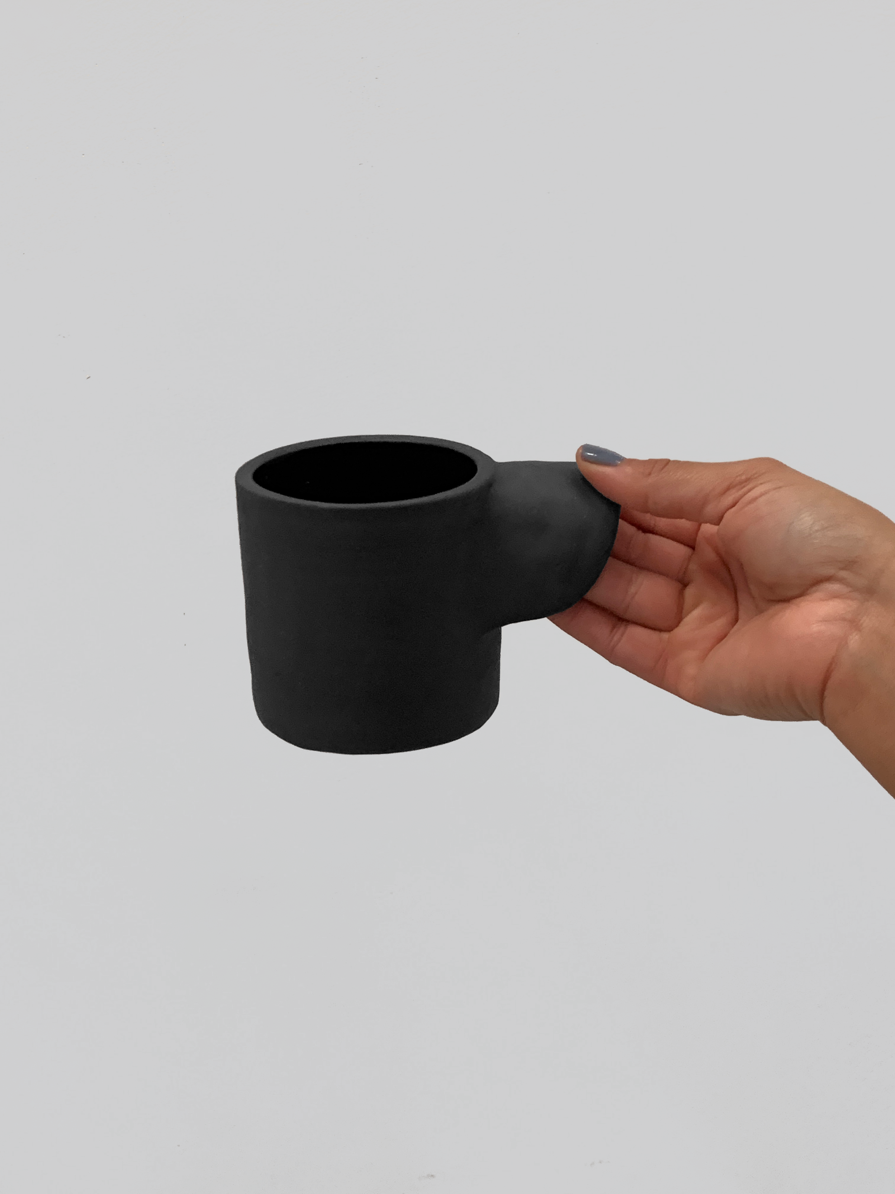 Black matte stoneware ceramic mug with an extended inward arching side handle.