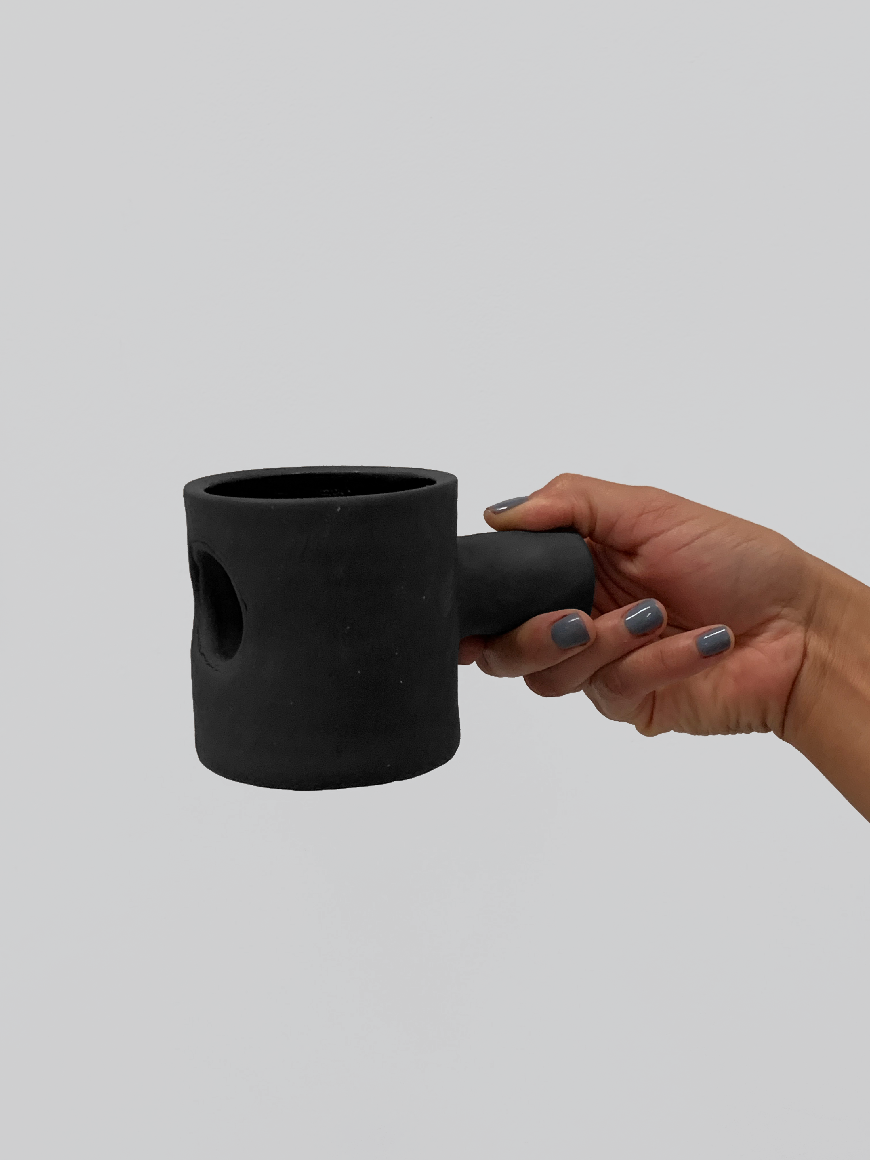 Black matte stoneware ceramic mug with a cylinder through the mug and extending out as the handle.