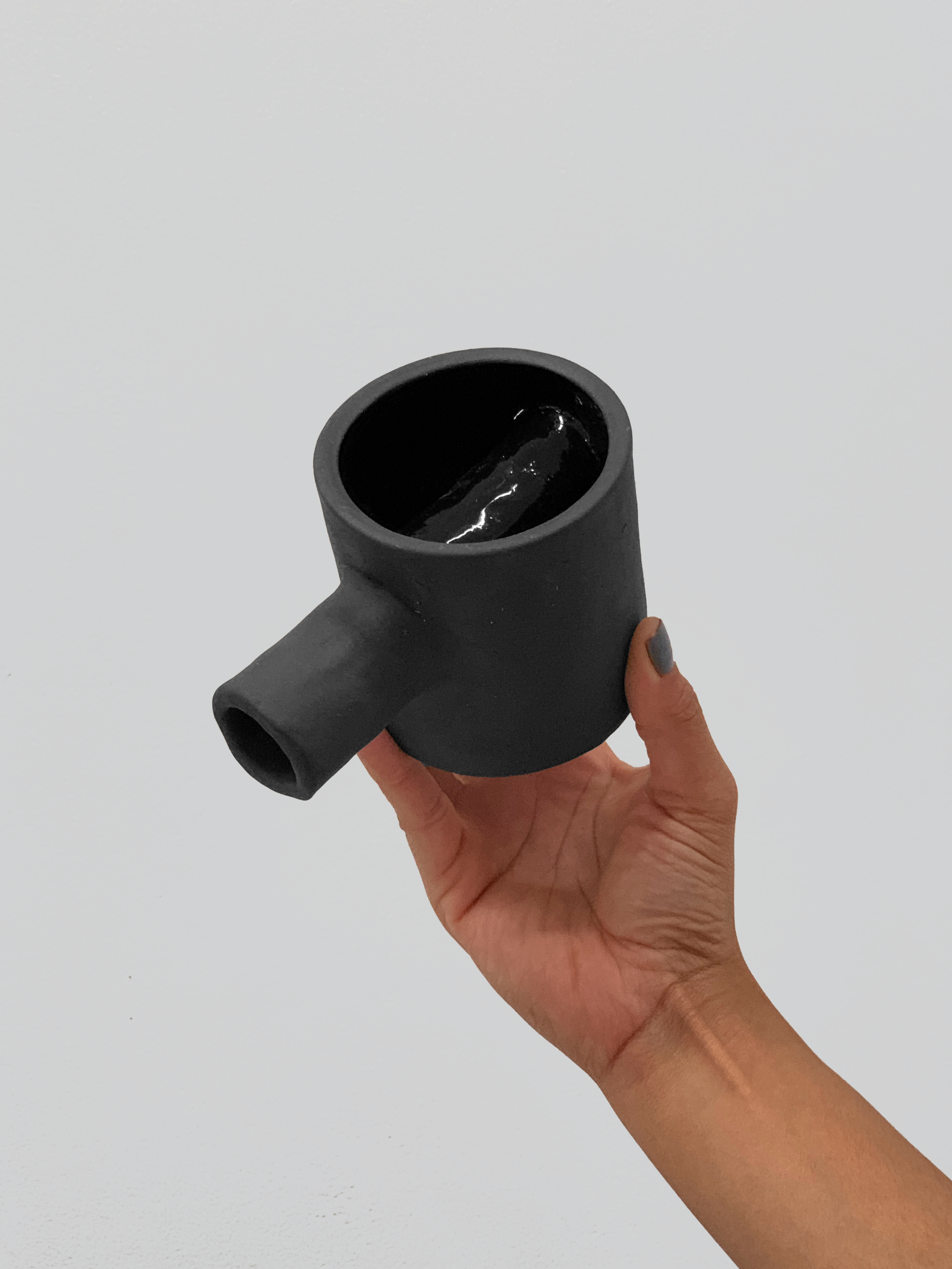 Black matte stoneware ceramic mug with a cylinder through the mug and extending out as the handle.