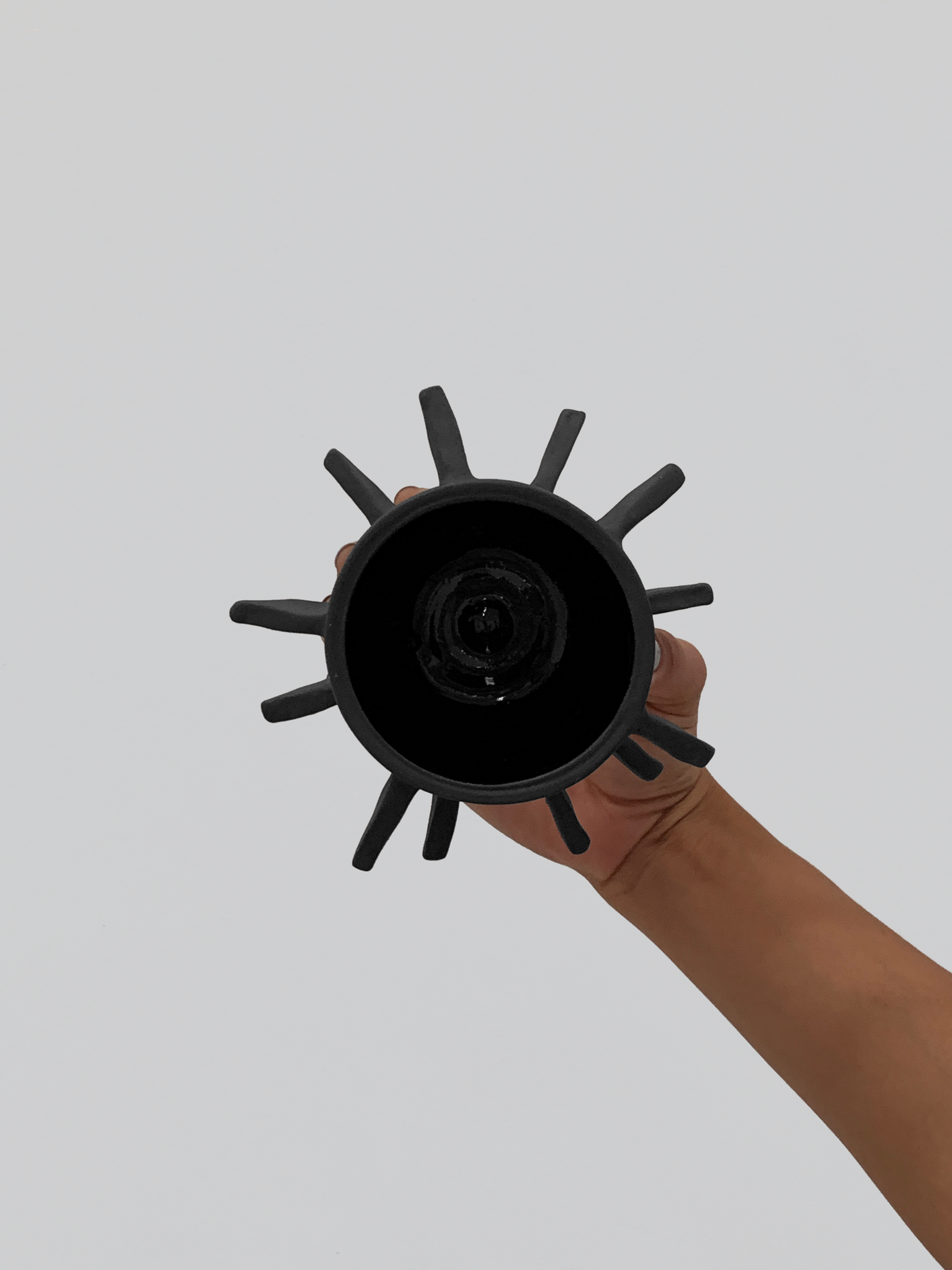 Black matte stoneware ceramic mug with outward facing triangles all throughout the mug as a handle.
