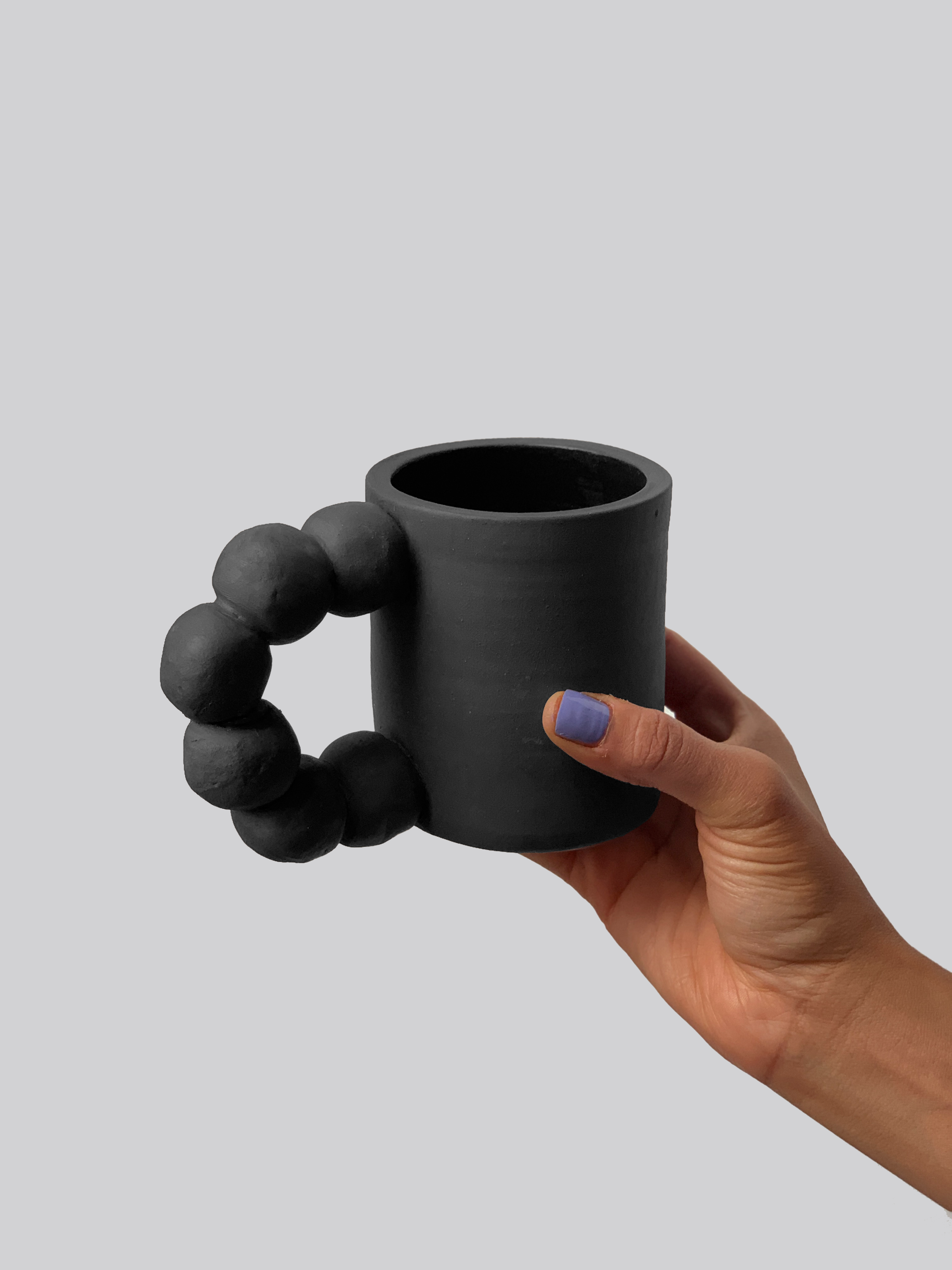 Black matte stoneware ceramic mug with six connected balls forming the handle.