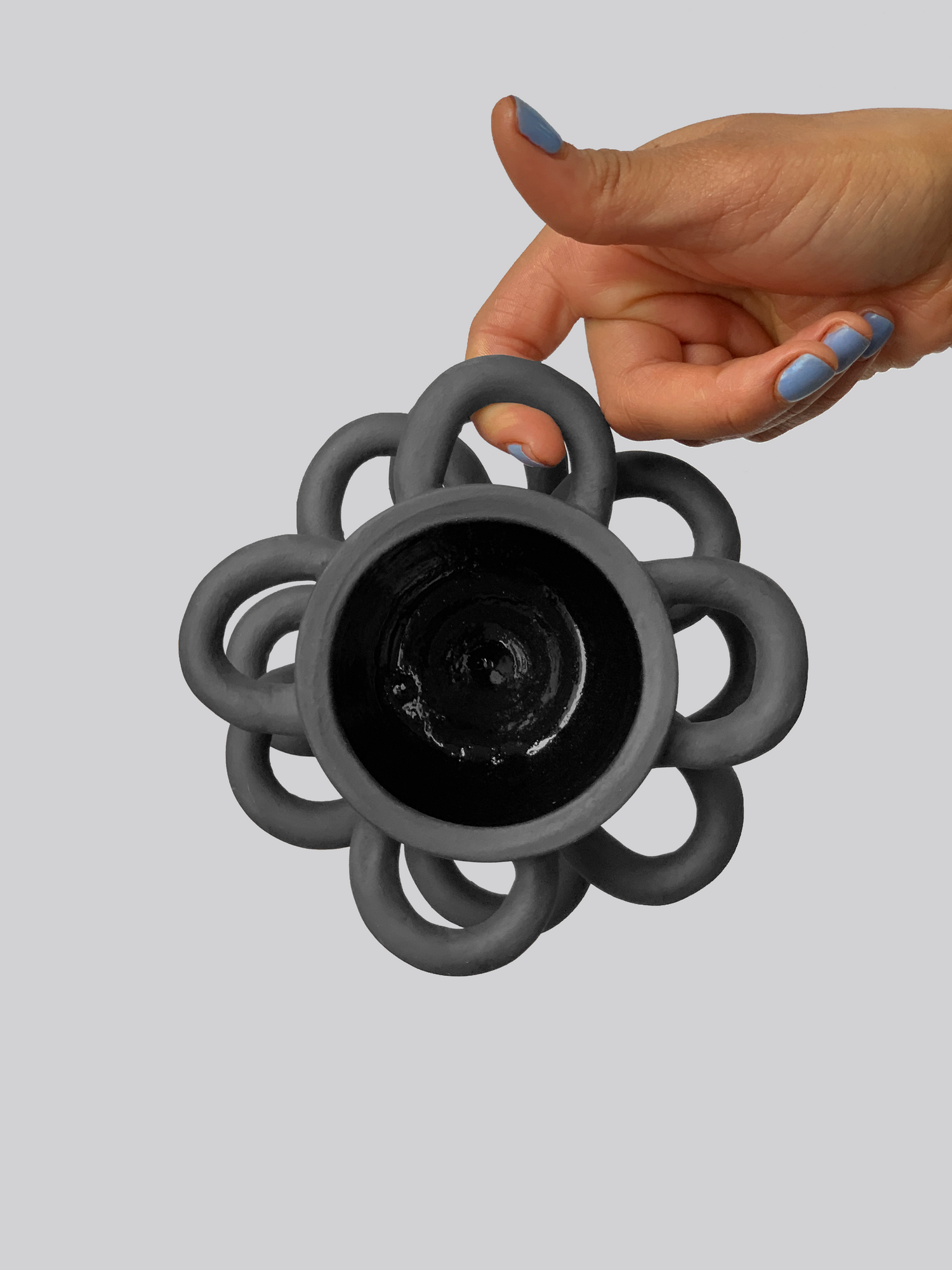 Black matte stoneware ceramic mug with half circle shapes throughout the exterior of the mug as the handles.