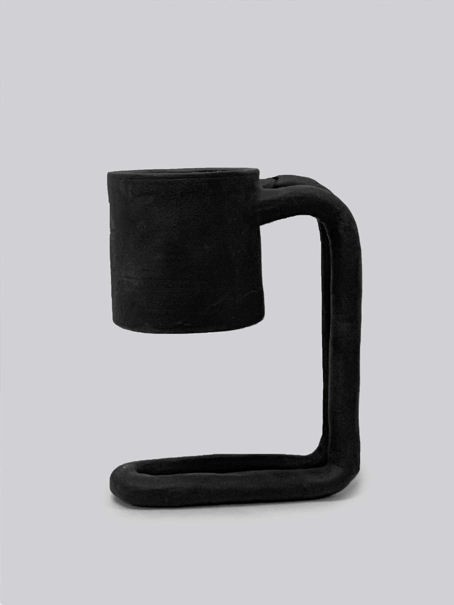 Black matte stoneware ceramic mug upon a tall fold over stand handle.