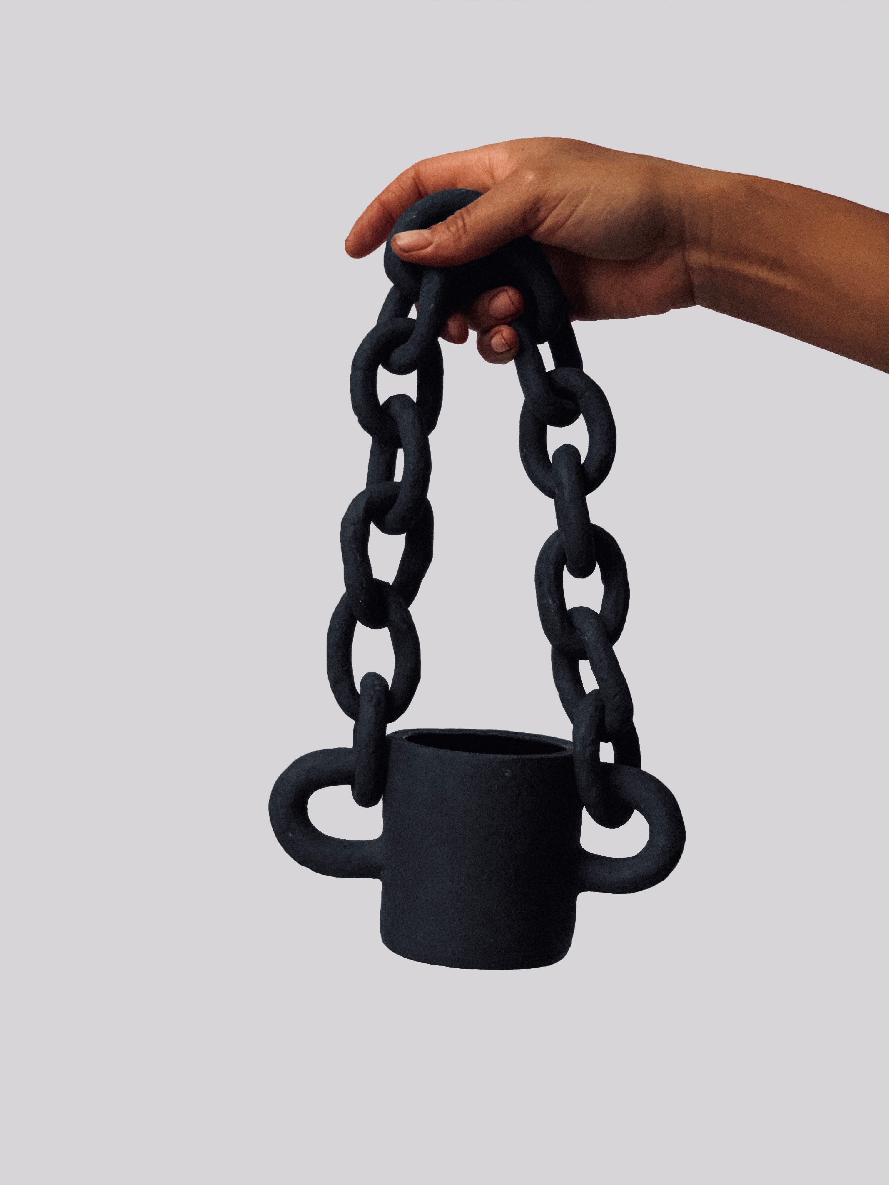 Black matte stoneware ceramic mug with a half shaped oval on each side of the mug and oval link chain passing through as the handle.