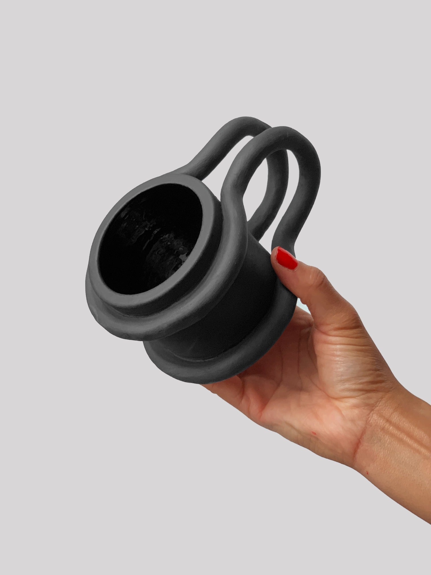 Black matte stoneware ceramic mug with two bar wrapping around each side of the mug and extending outwards as the handle.