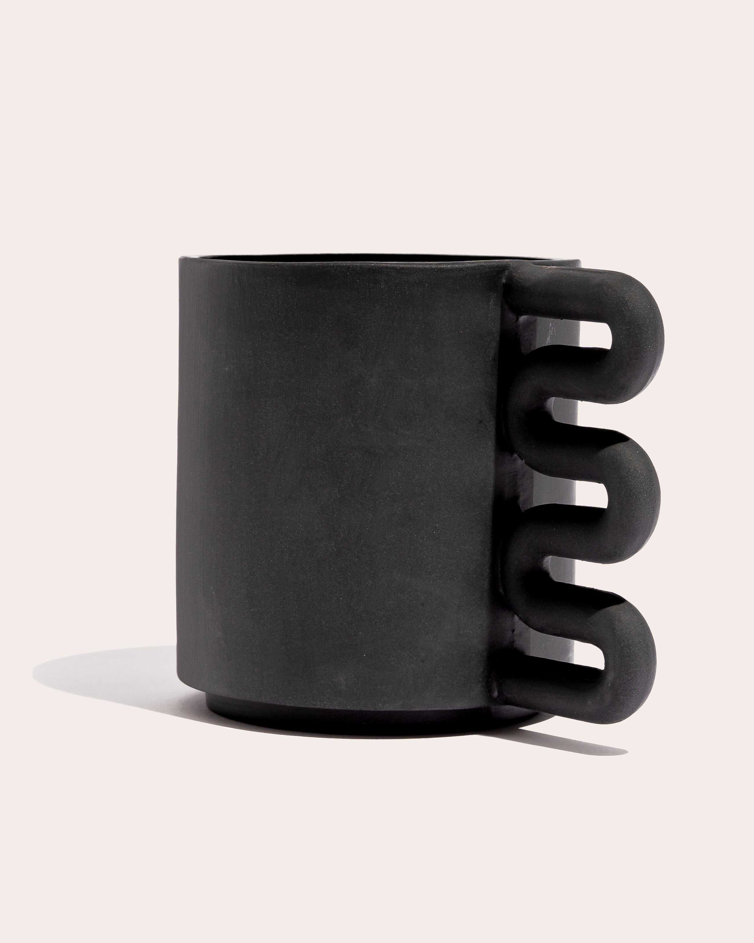 Black matte stoneware ceramic mug with a squiggle shaped handle.