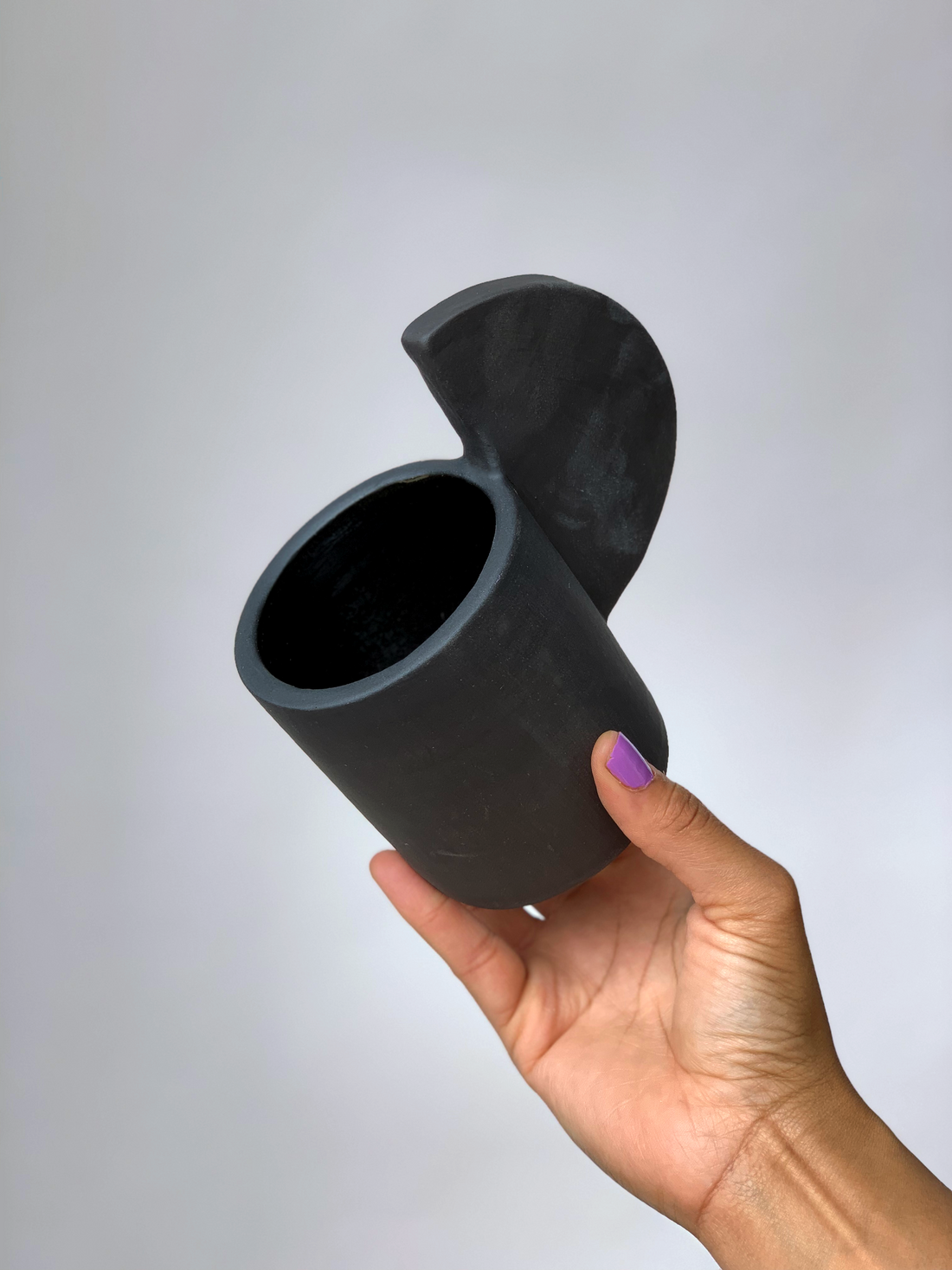 Black matte stoneware ceramic mug with an extended half circle handle.