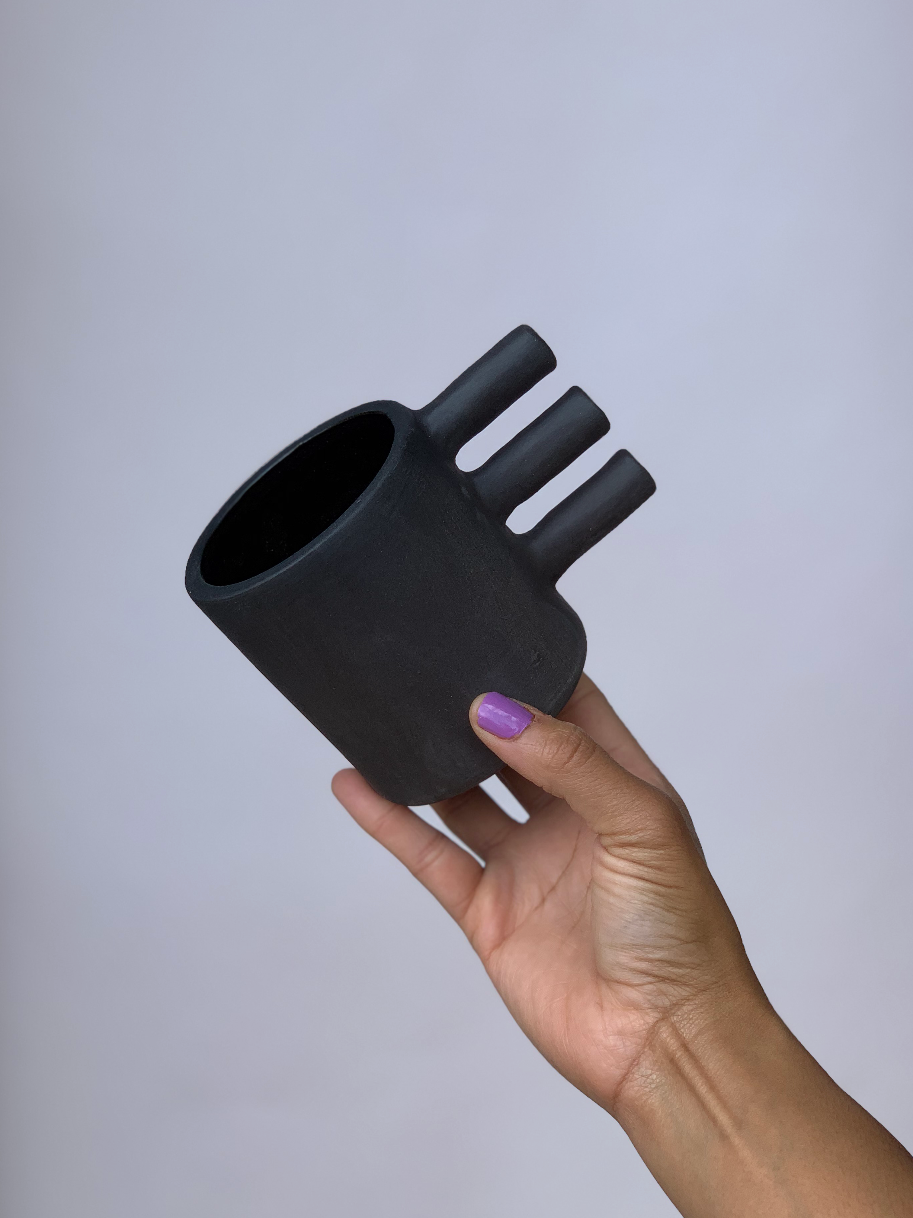Black matte stoneware ceramic mug with a three bar handle.