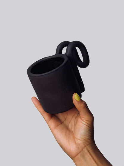 Black matte stoneware ceramic mug with a fold over bar handle.