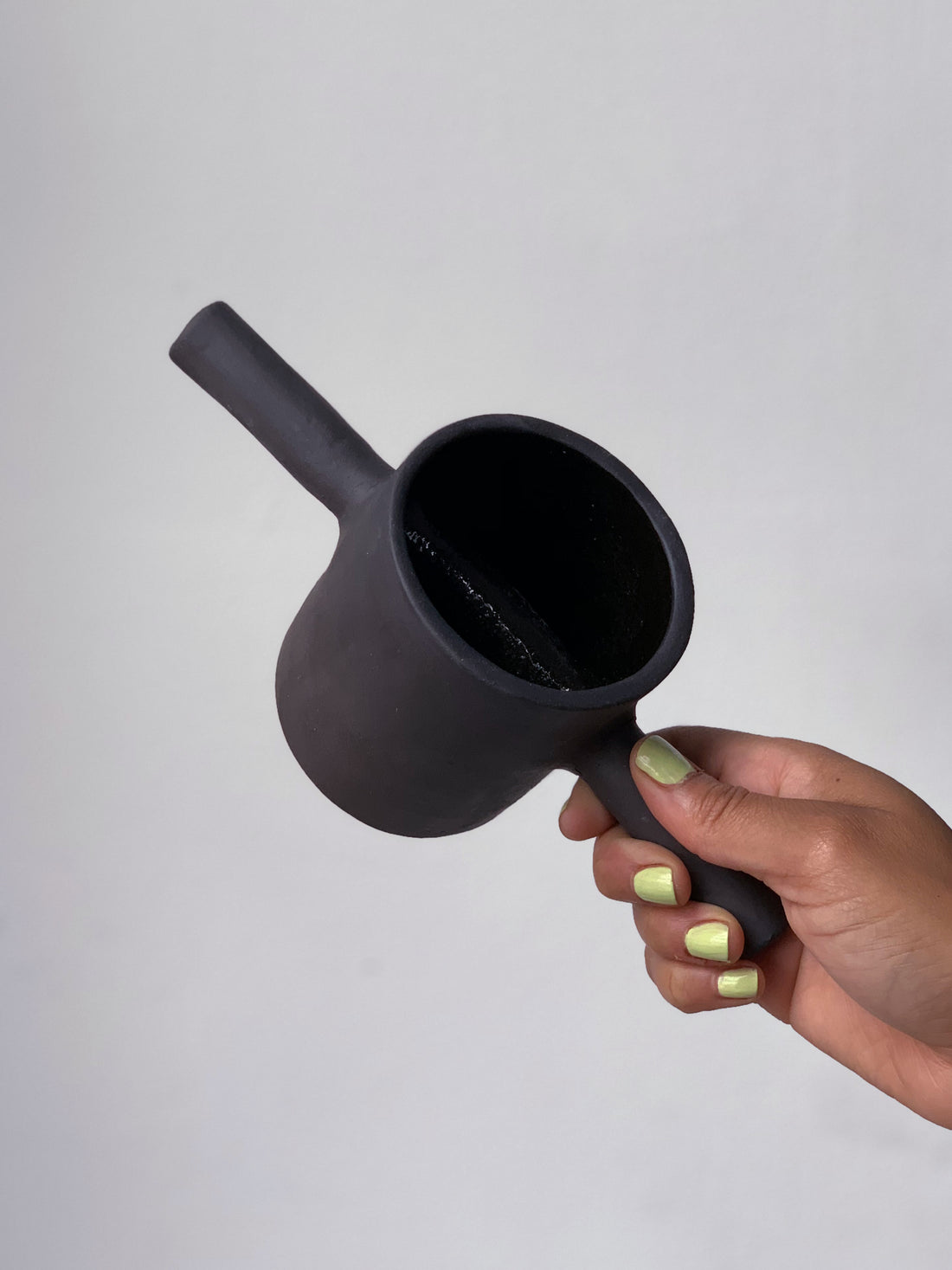 Black matte stoneware ceramic mug with a  bar on each side of the mug as the handle. 