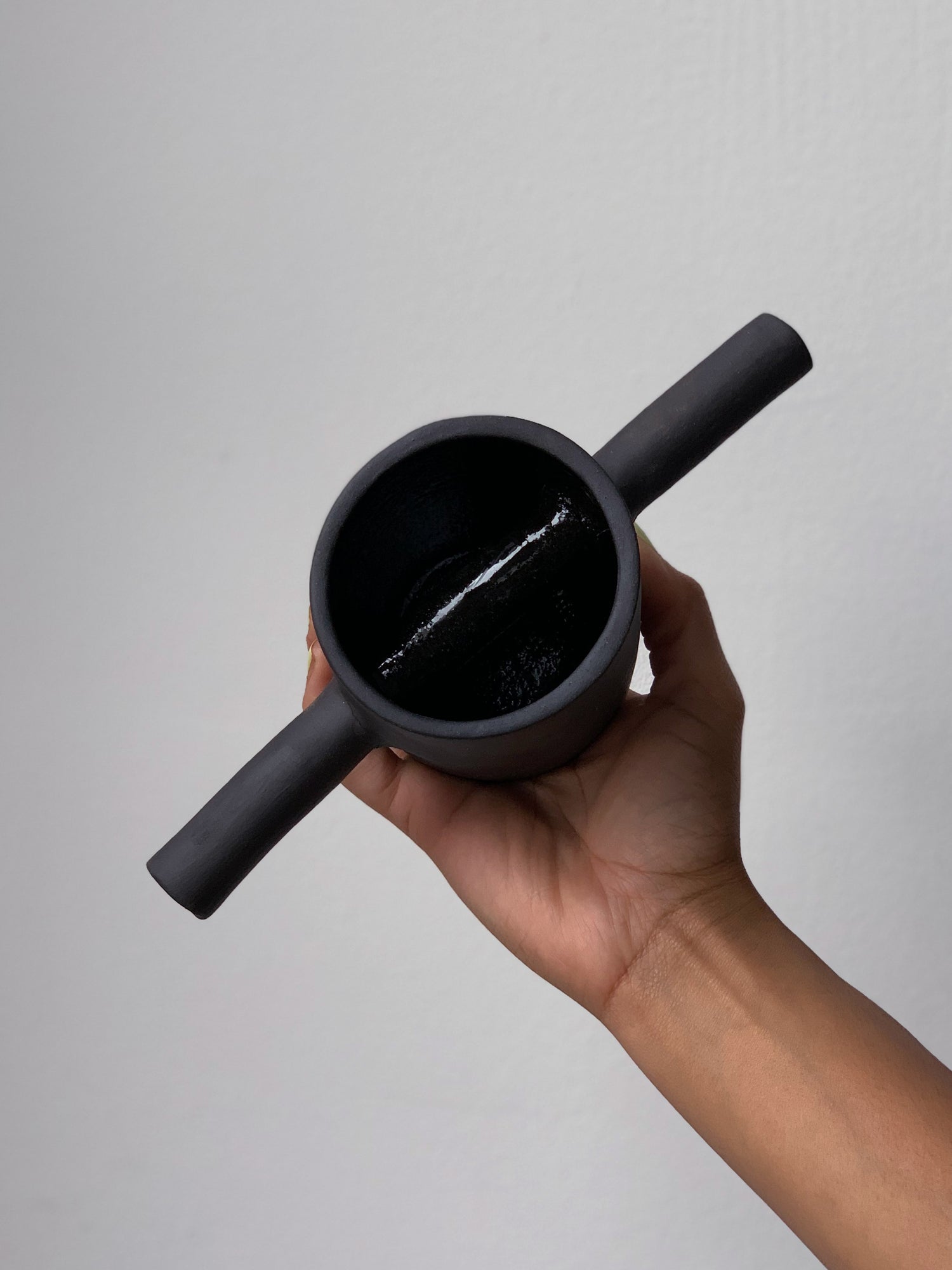 Black matte stoneware ceramic mug with a bar on each side of the mug as the handle.