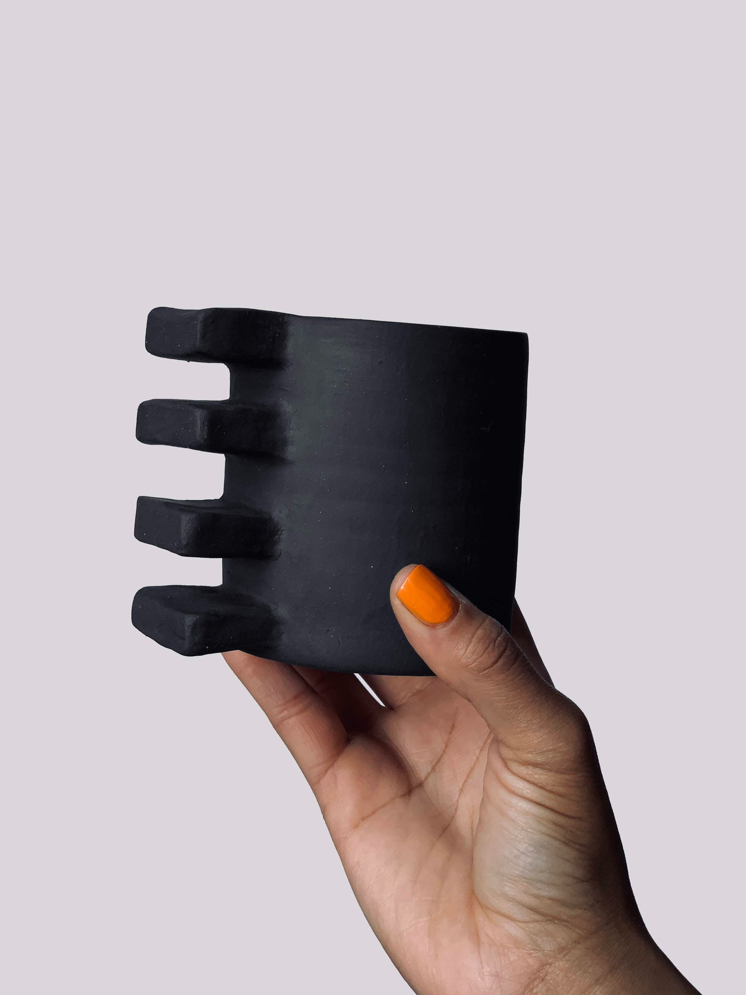 Black matte stoneware ceramic mug with four extended rectangles as the handle.
