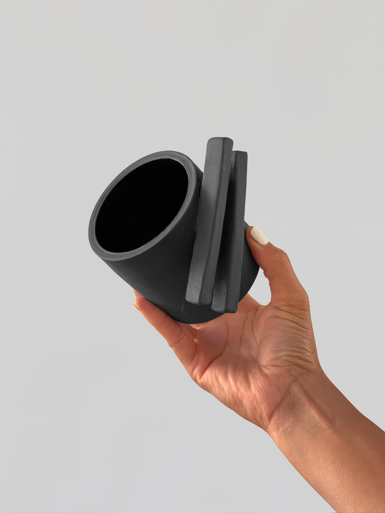 Black matte stoneware ceramic mug with two long rectangle shapes on the side of the mug as the handle.