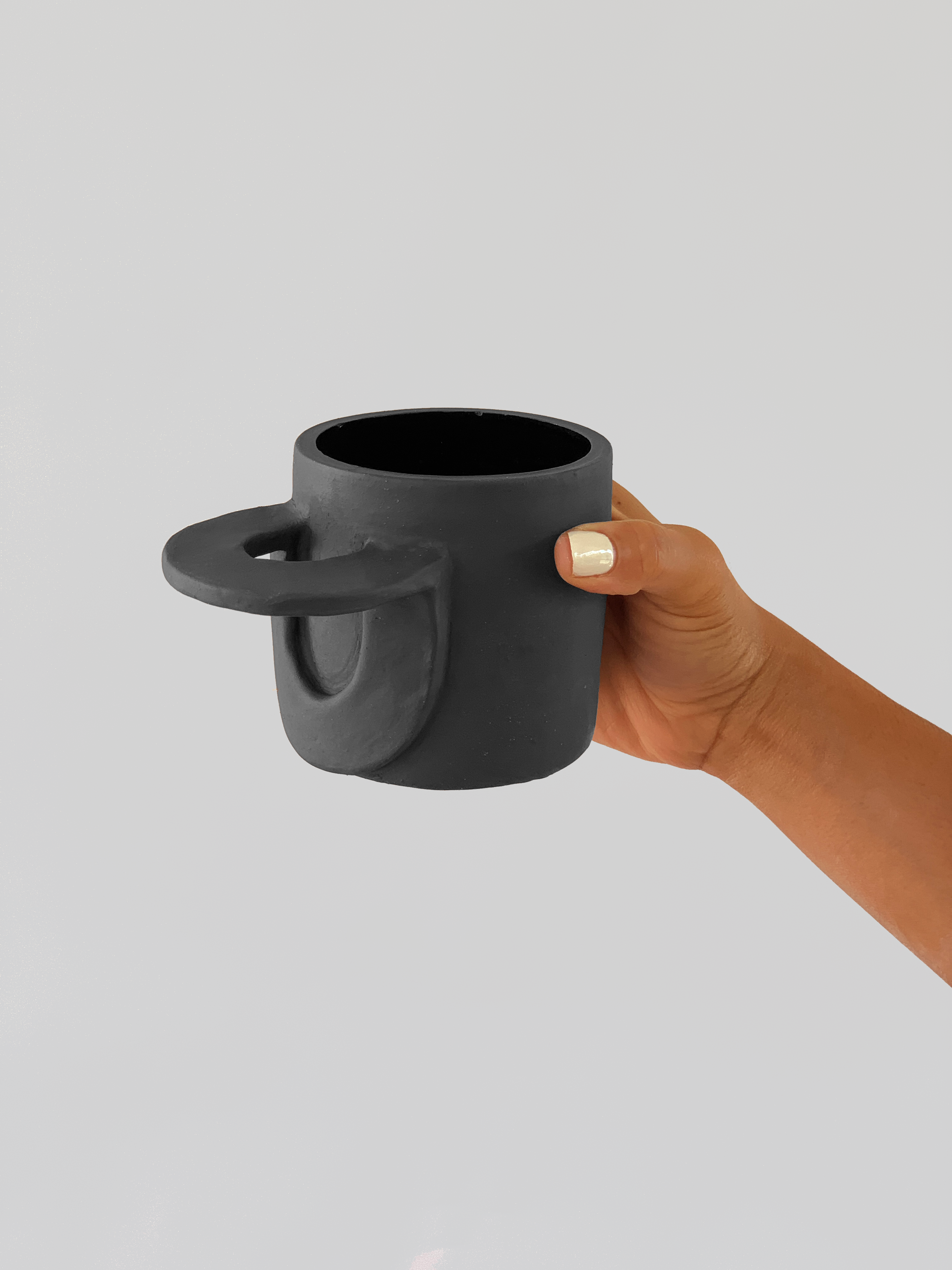 Black matte stoneware ceramic mug with a  wide oval half folded over handle.