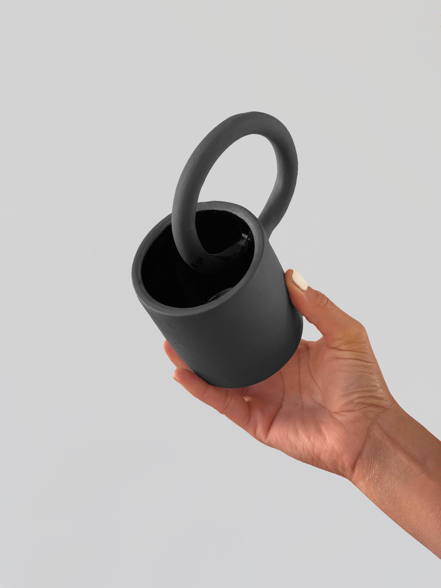 Black matte stoneware ceramic mug with a full circle through center handle.