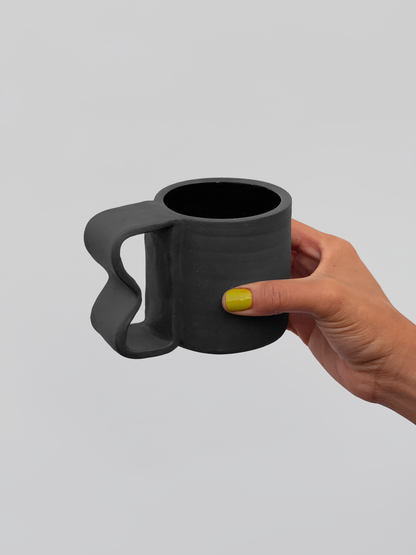 Black matte stoneware ceramic mug with a wide wavy inlet handle.