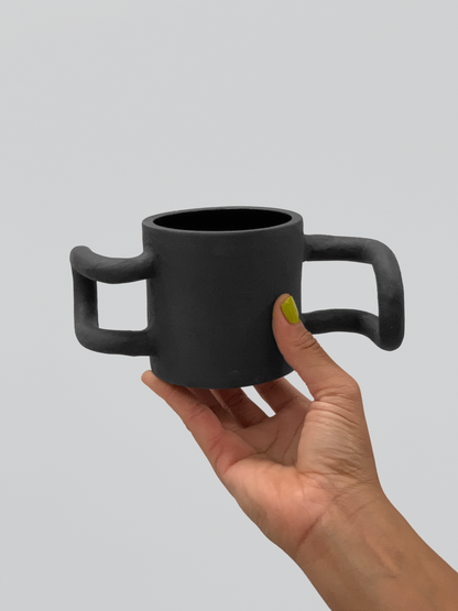 Black matte stoneware ceramic mug with propeller fin handles on each side.