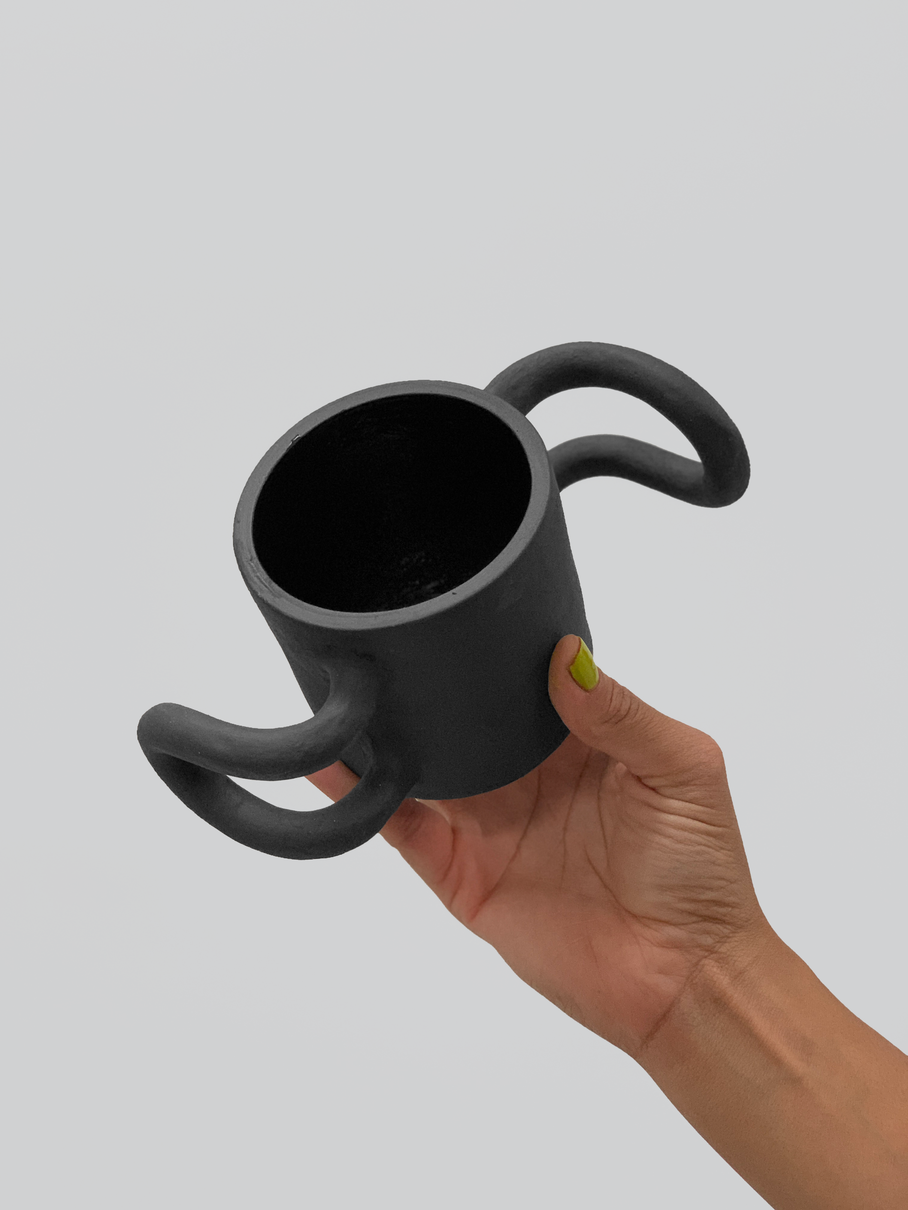 Black matte stoneware ceramic mug with propeller fin handles on each side. 
