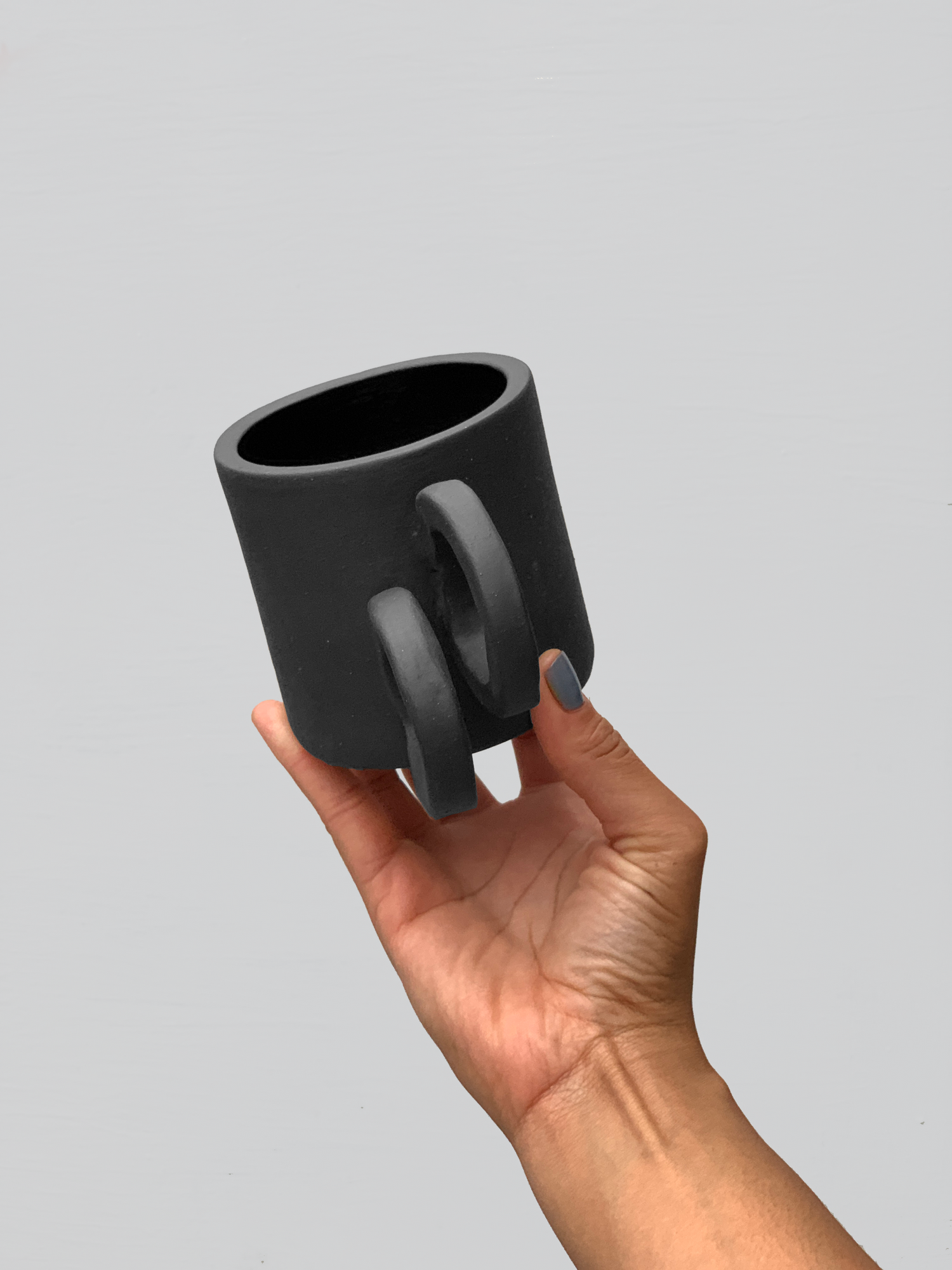 Black matte stoneware ceramic mug with side staggered full circle handles.