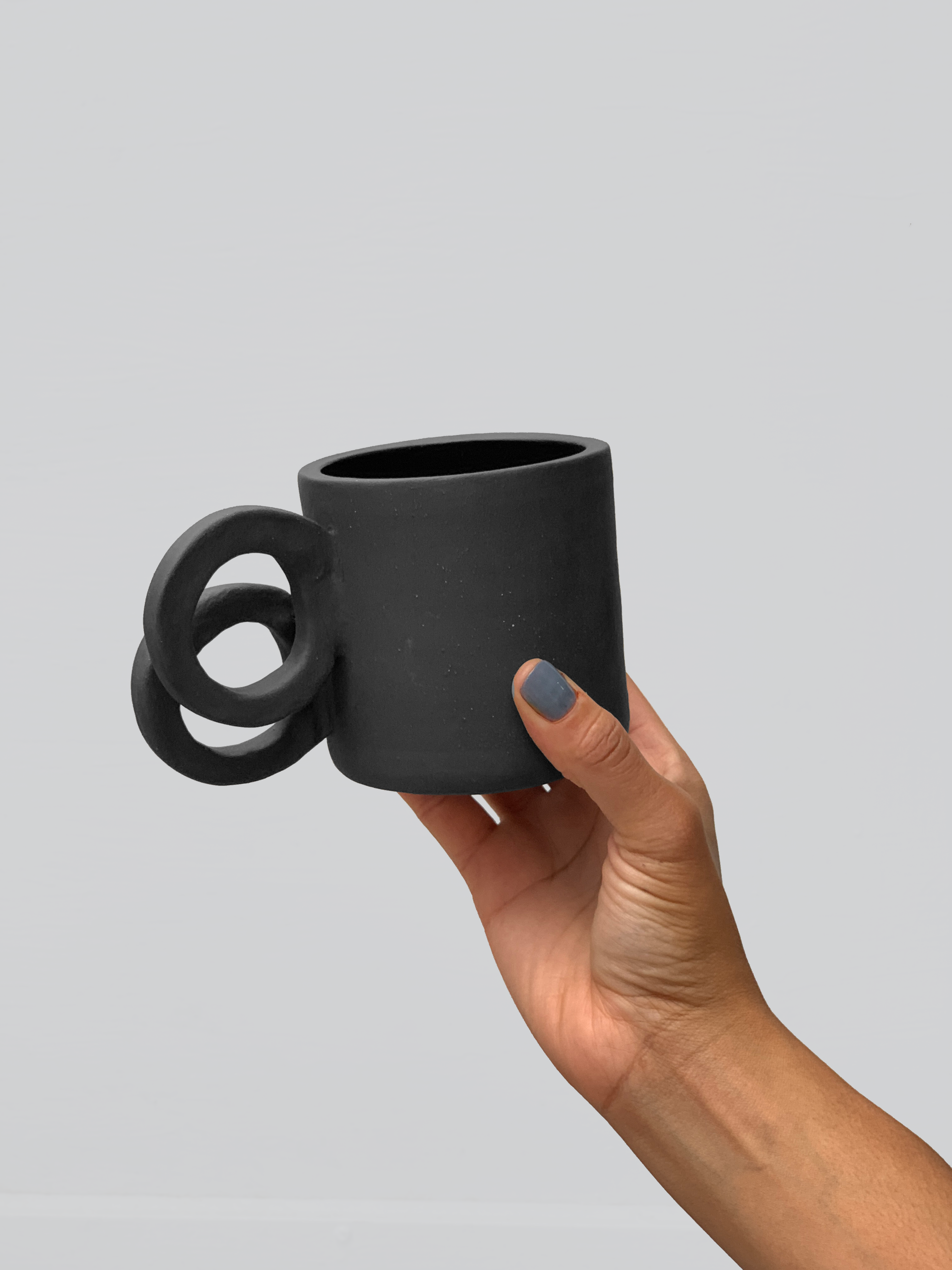 Black matte stoneware ceramic mug with side staggered full circle handles.