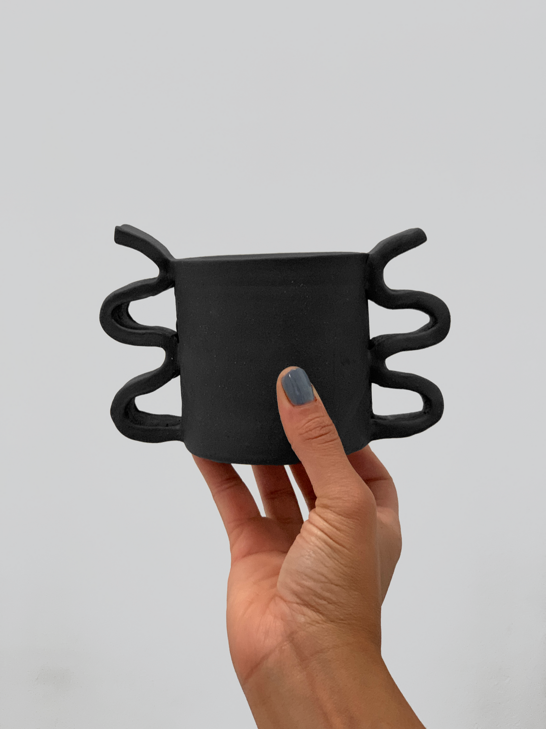 Black matte stoneware ceramic mug with double sided wide squiggle handles.