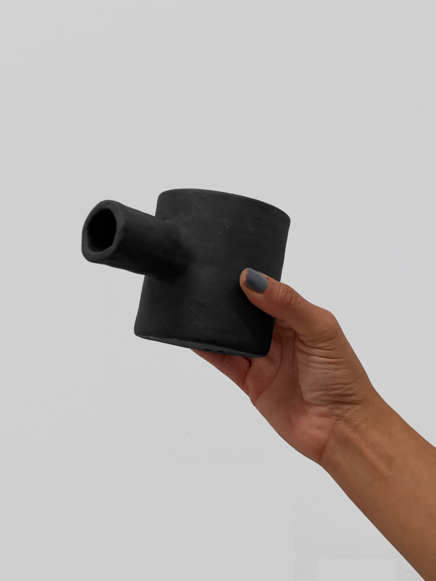 Black matte stoneware ceramic mug with a cylinder through the mug and extending out as the handle.