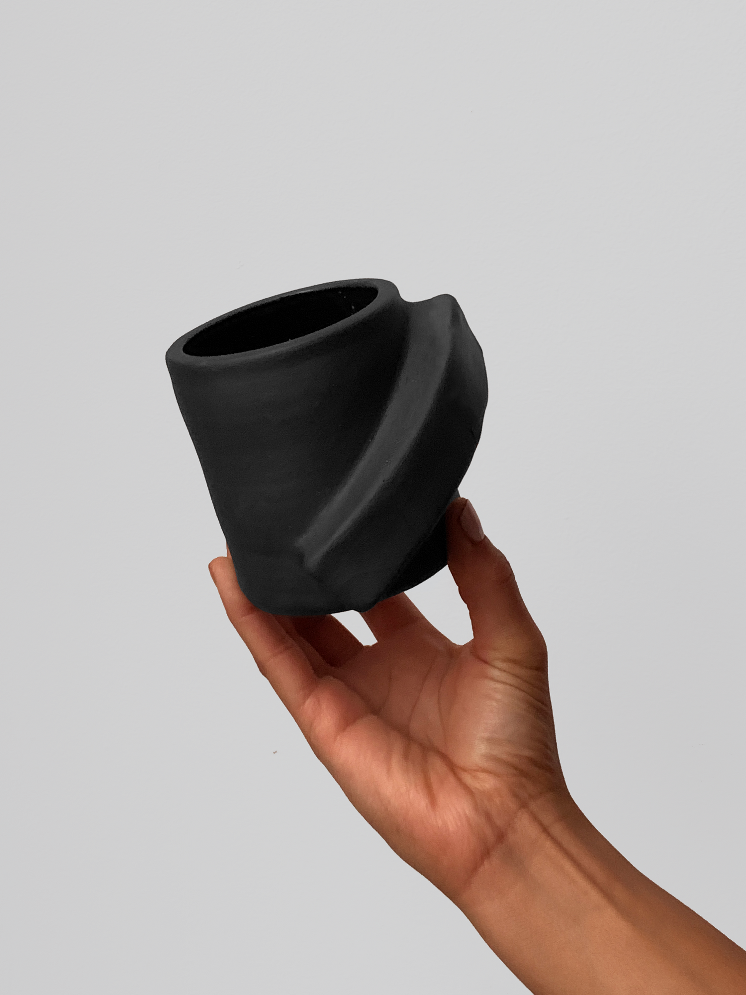 Black matte stoneware ceramic mug with thick sloped rectangle side handle.