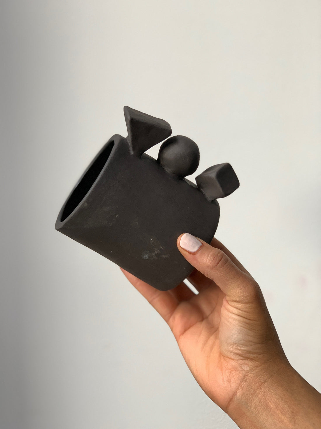 Black matte stoneware ceramic mug with three extended shapes as the handle.
