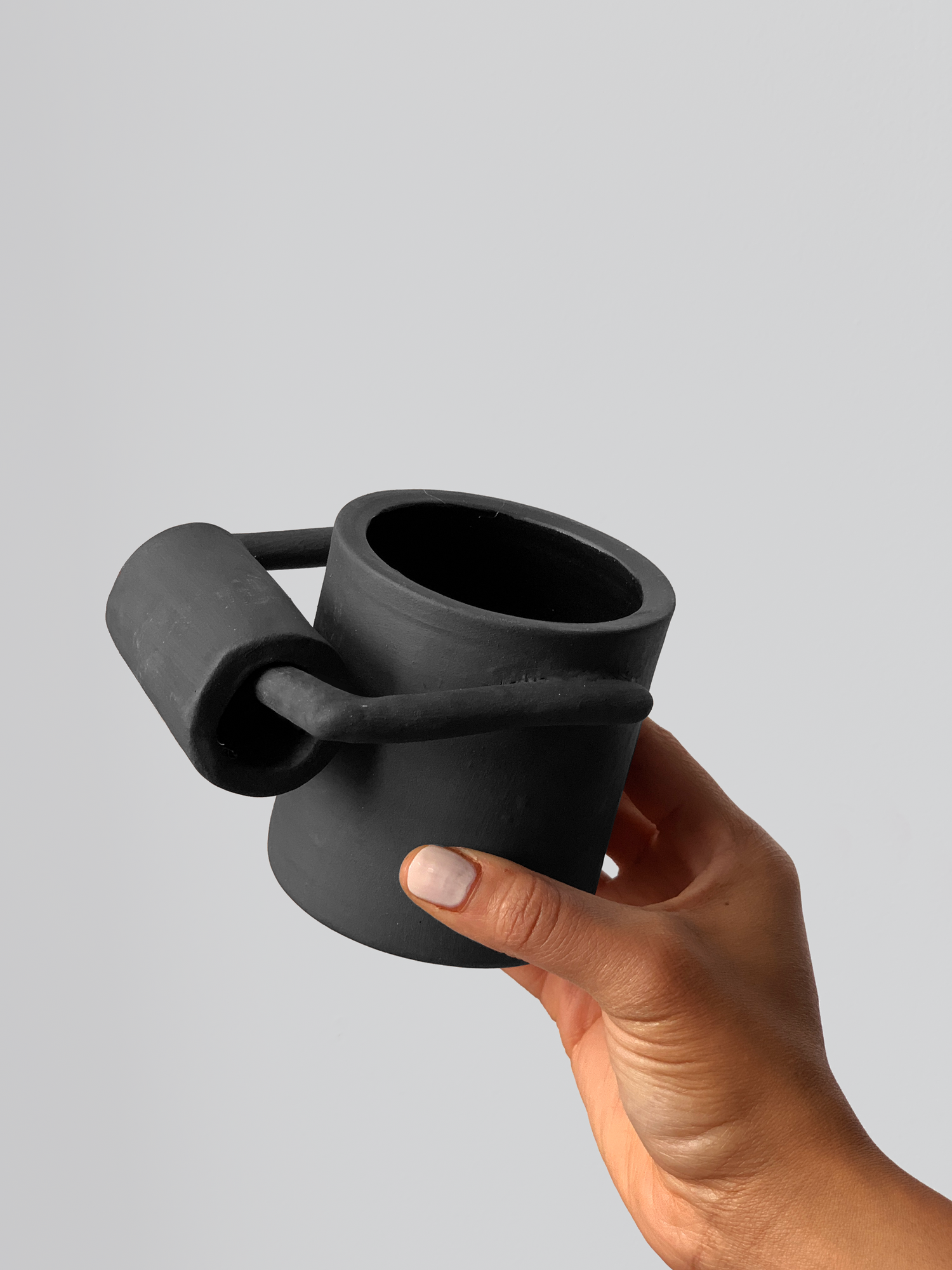 Black matte stoneware ceramic mug with an extended cylinder roll holder handle.