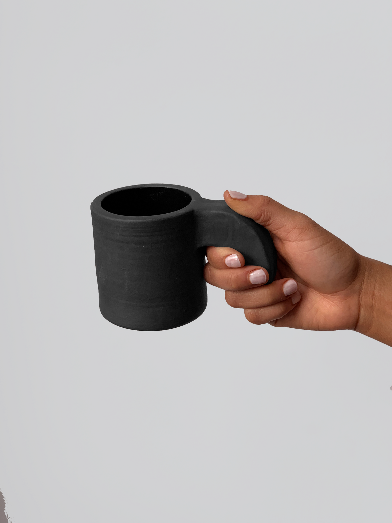 Black matte stoneware ceramic mug with a thick downward facing curved handle.