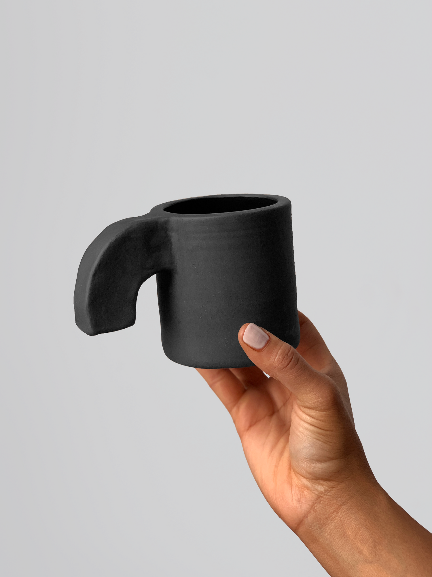 Black matte stoneware ceramic mug with a thick downward facing curved handle.