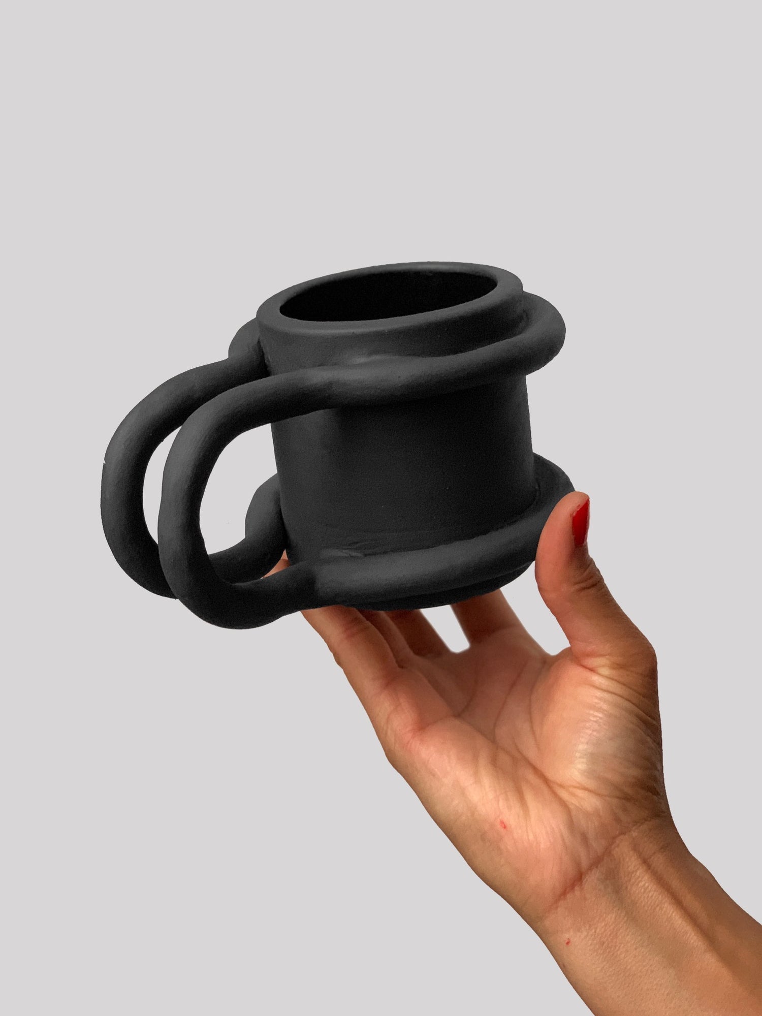 Black matte stoneware ceramic mug with two bar wrapping around each side of the mug and extending outwards as the handle.