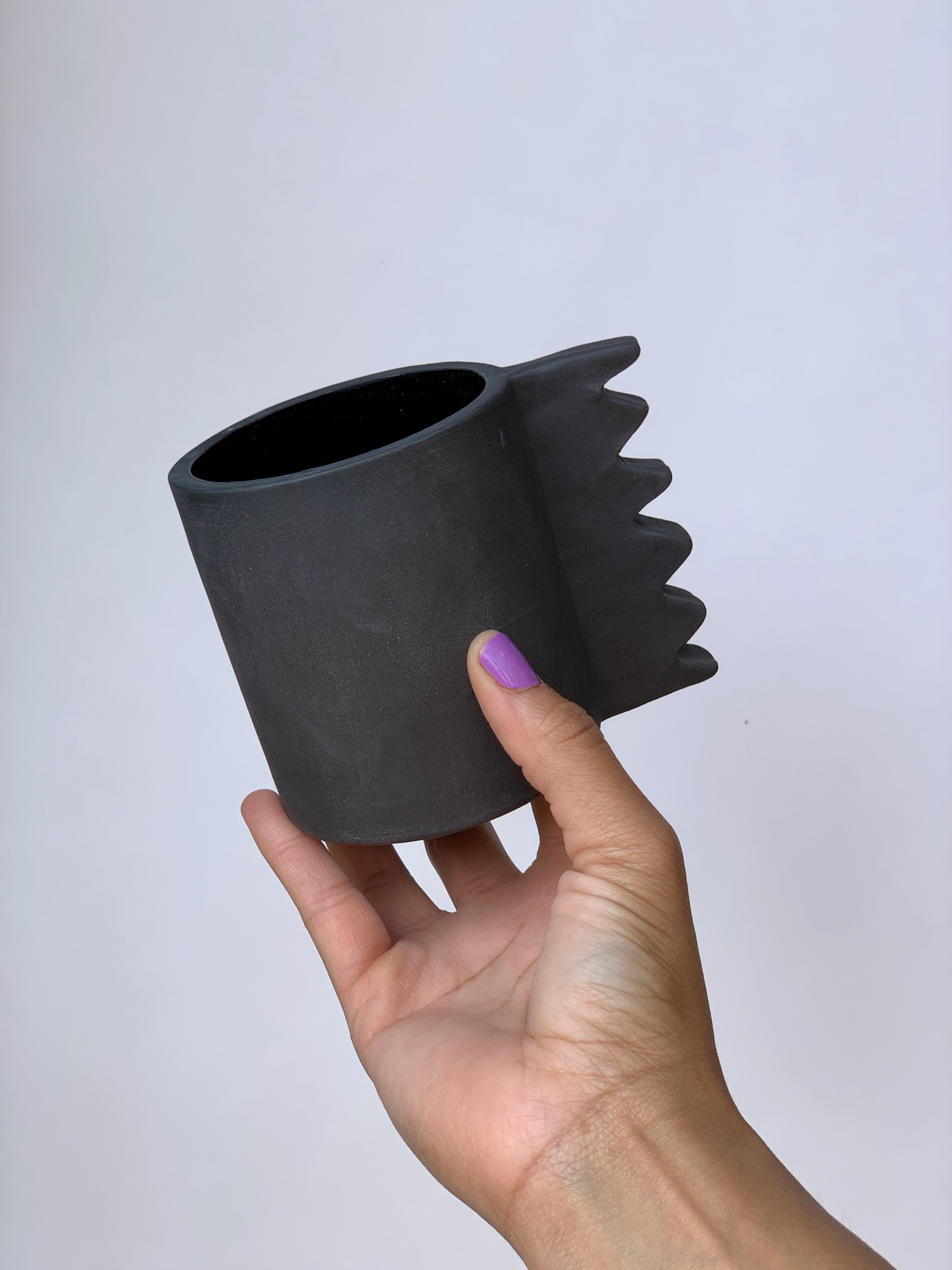Black matte stoneware ceramic mug with a  wide zigzag handle.