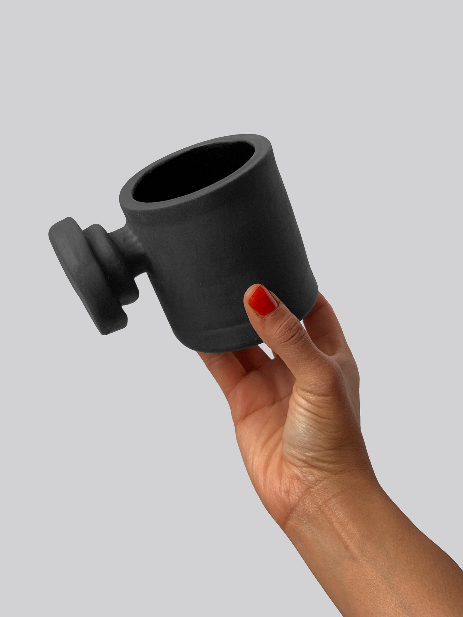 Black matte stoneware ceramic mug with a layered circular knob handle.