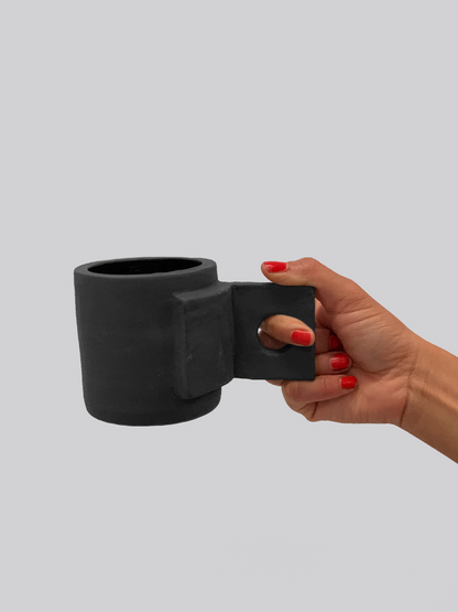 Black matte stoneware ceramic mug with square fold open handle and circle cutout center.