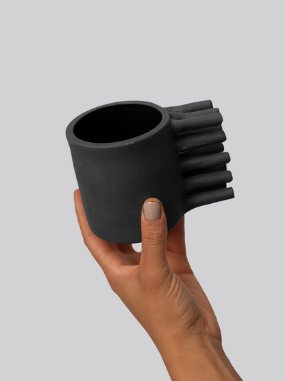 Black matte stoneware ceramic mug with extended bristles on the side of the mug as the handle.