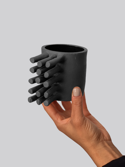 Black matte stoneware ceramic mug with extended bristles on the side of the mug as the handle.