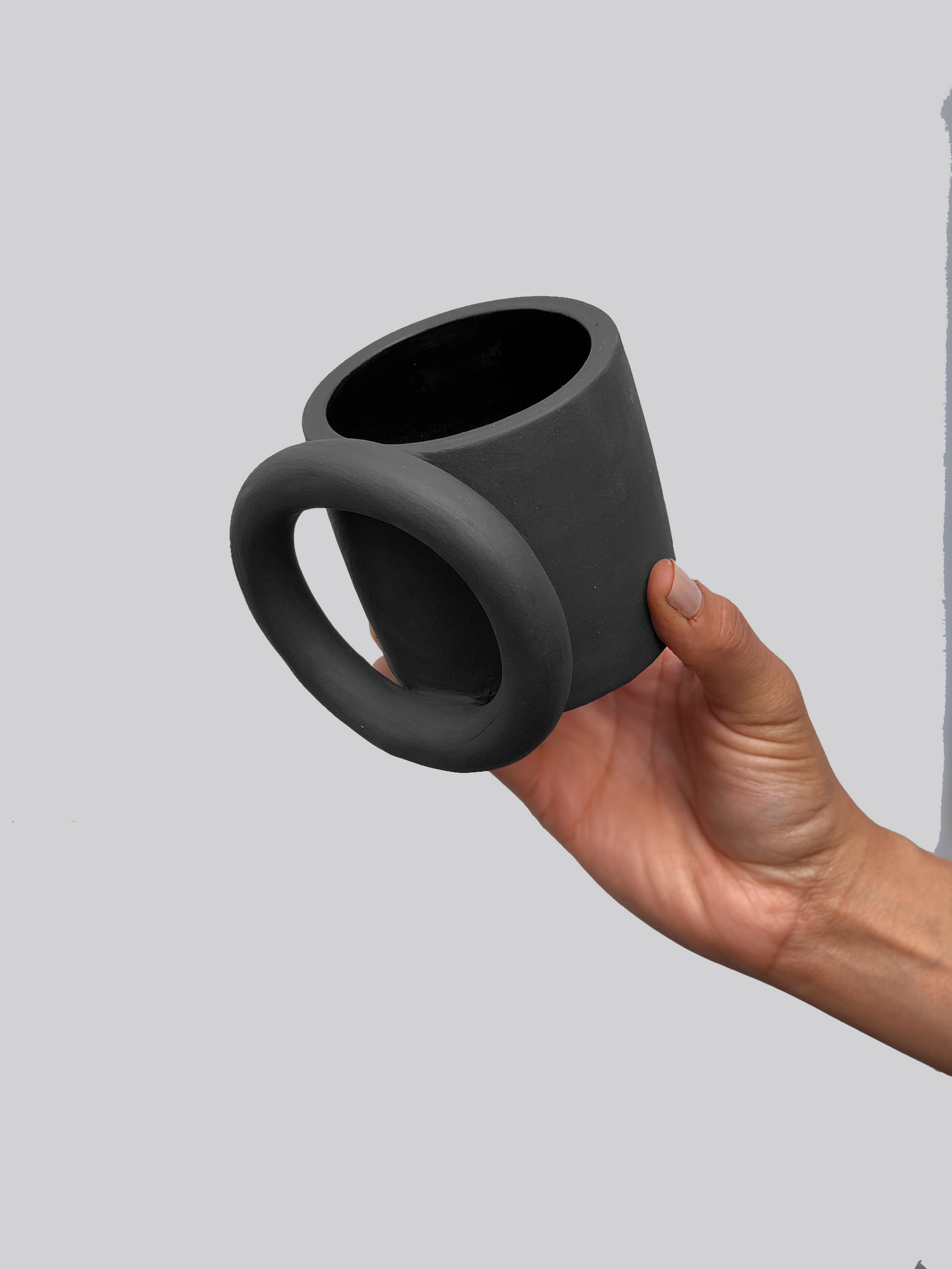 Black matte ceramic mug with a thick full circle ring as the handle.